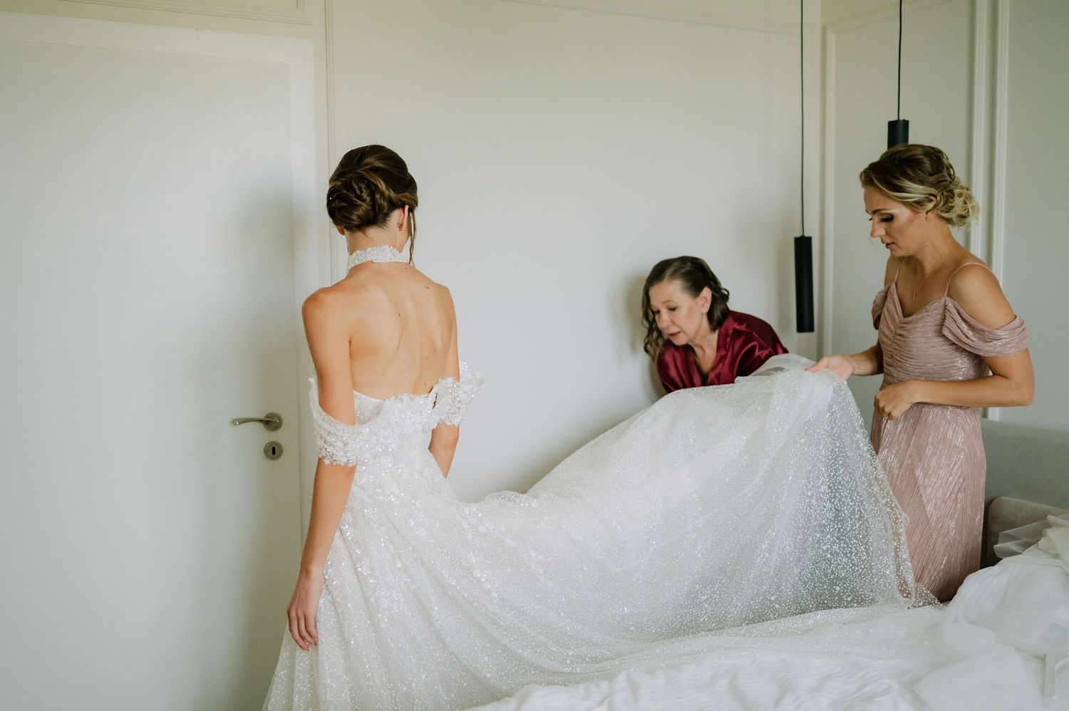 A bride in a white dress getting ready with her wedding party in a bright indoor setting.