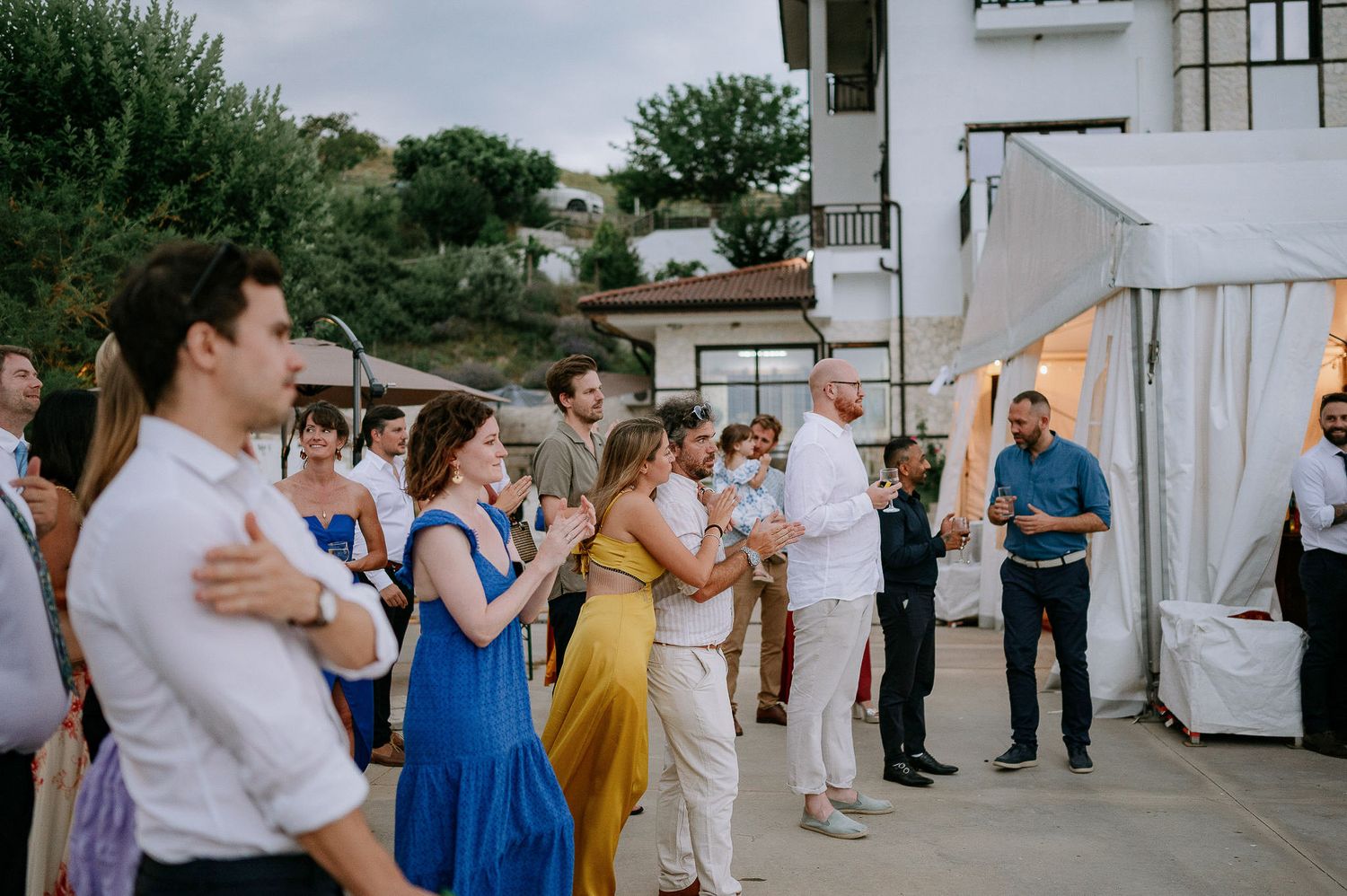 Wedding guests gather on a patio during an outdoor reception.