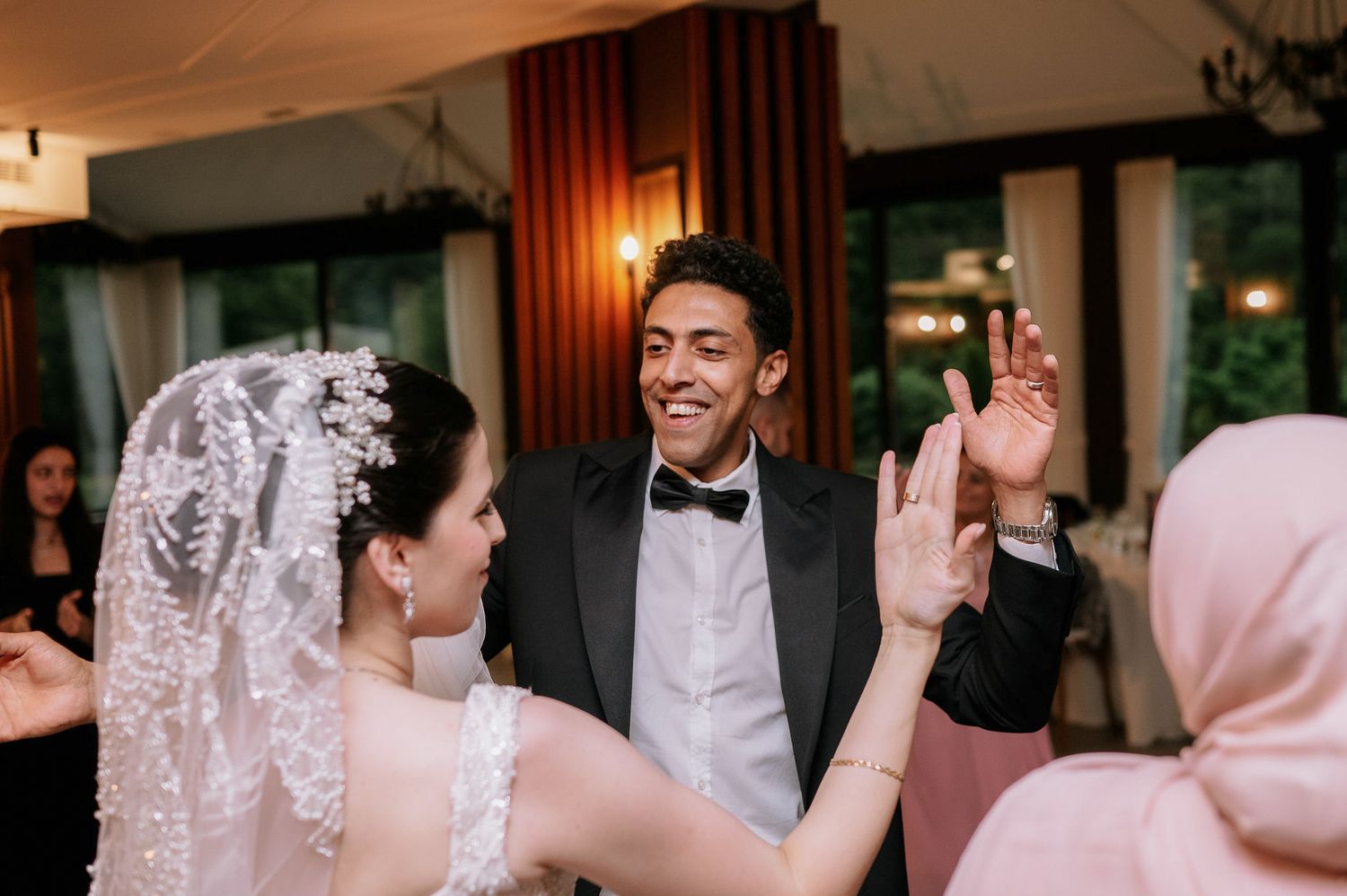 Joyful wedding celebration with guests dancing together in an elegant indoor reception space.