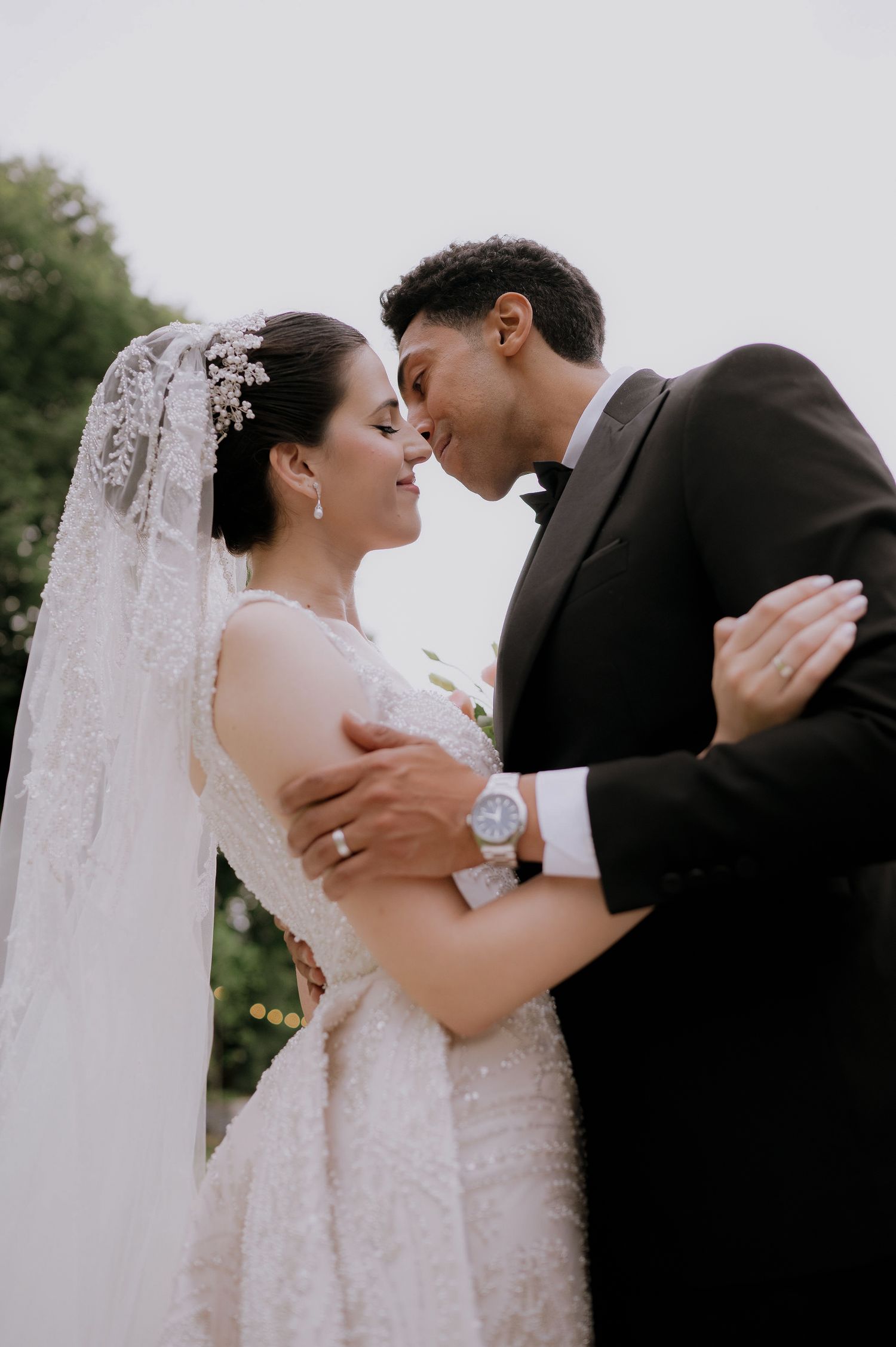 A tender romantic moment between newlyweds wearing formal wedding attire.