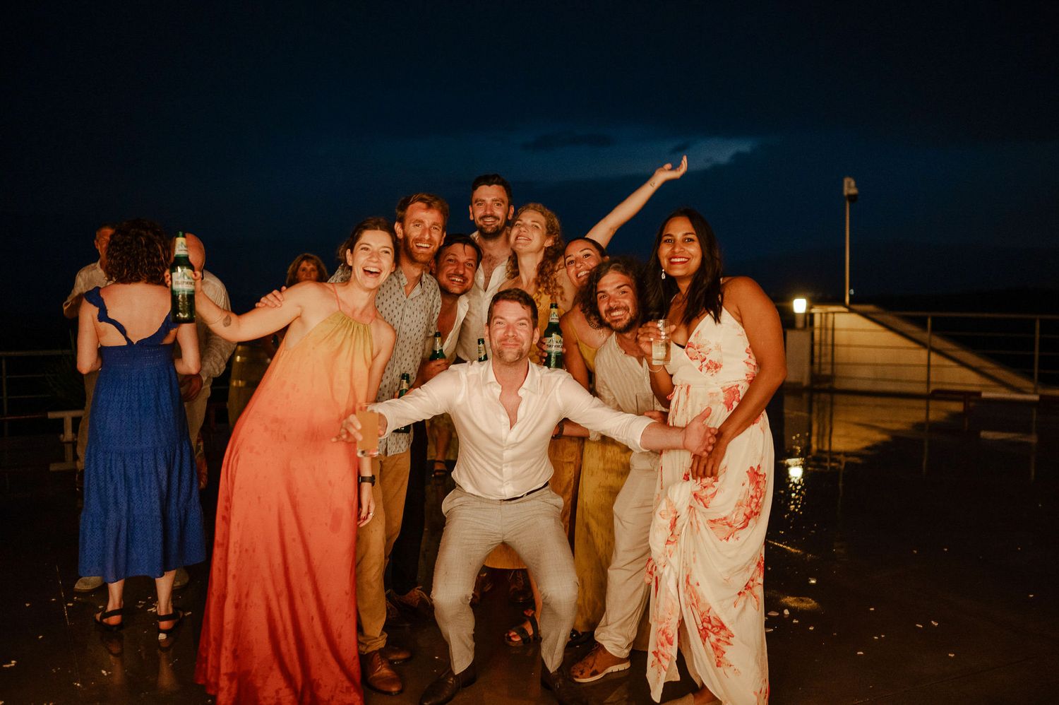 Large group of wedding guests dancing and celebrating outdoors at night.