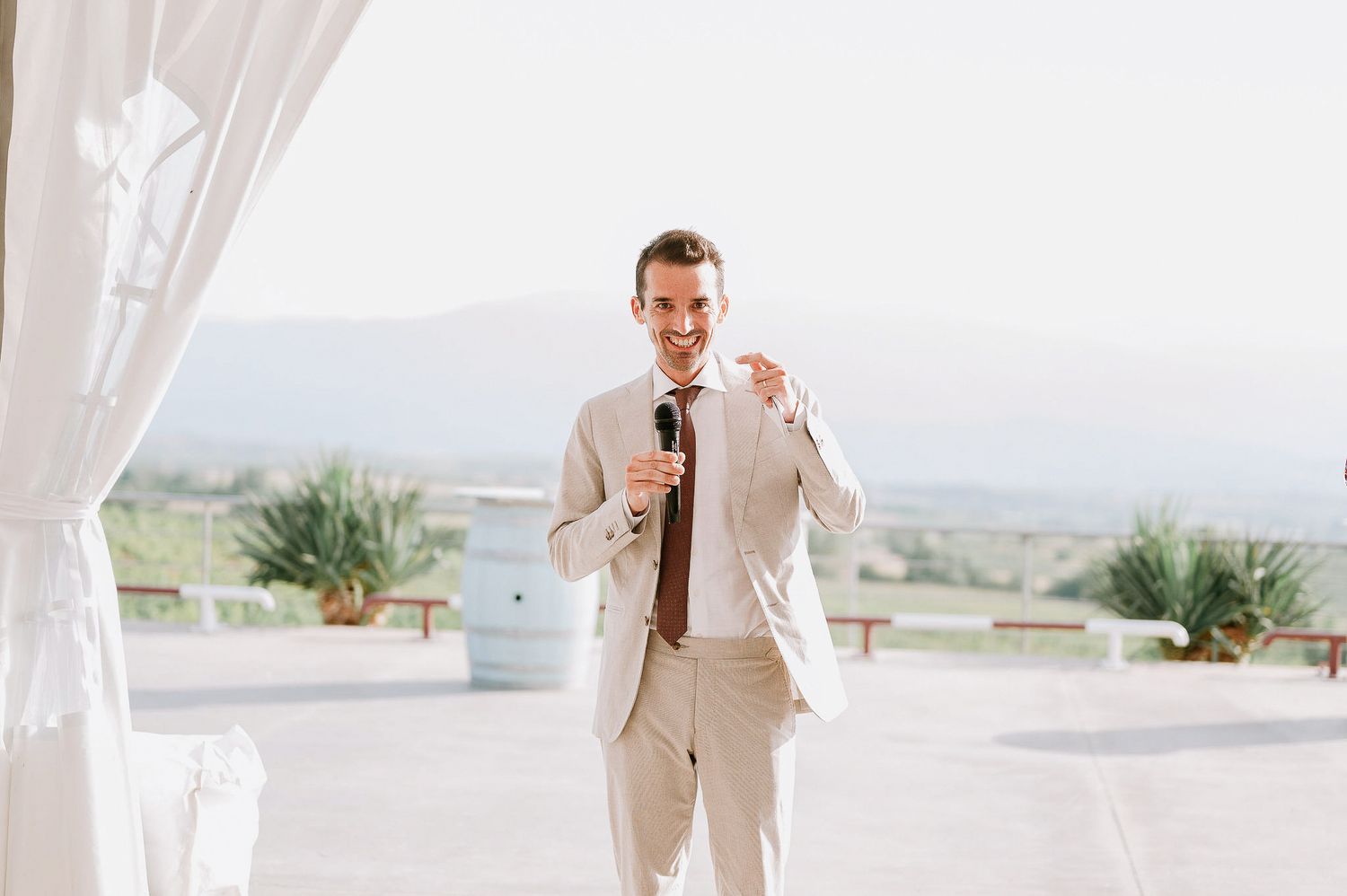 Outdoor wedding ceremony setup with white chairs and floral arrangements against a scenic mountain backdrop.