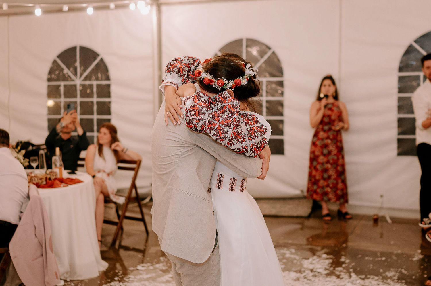 Guests enjoy a lively celebration inside an elegant white tent with string lights overhead.