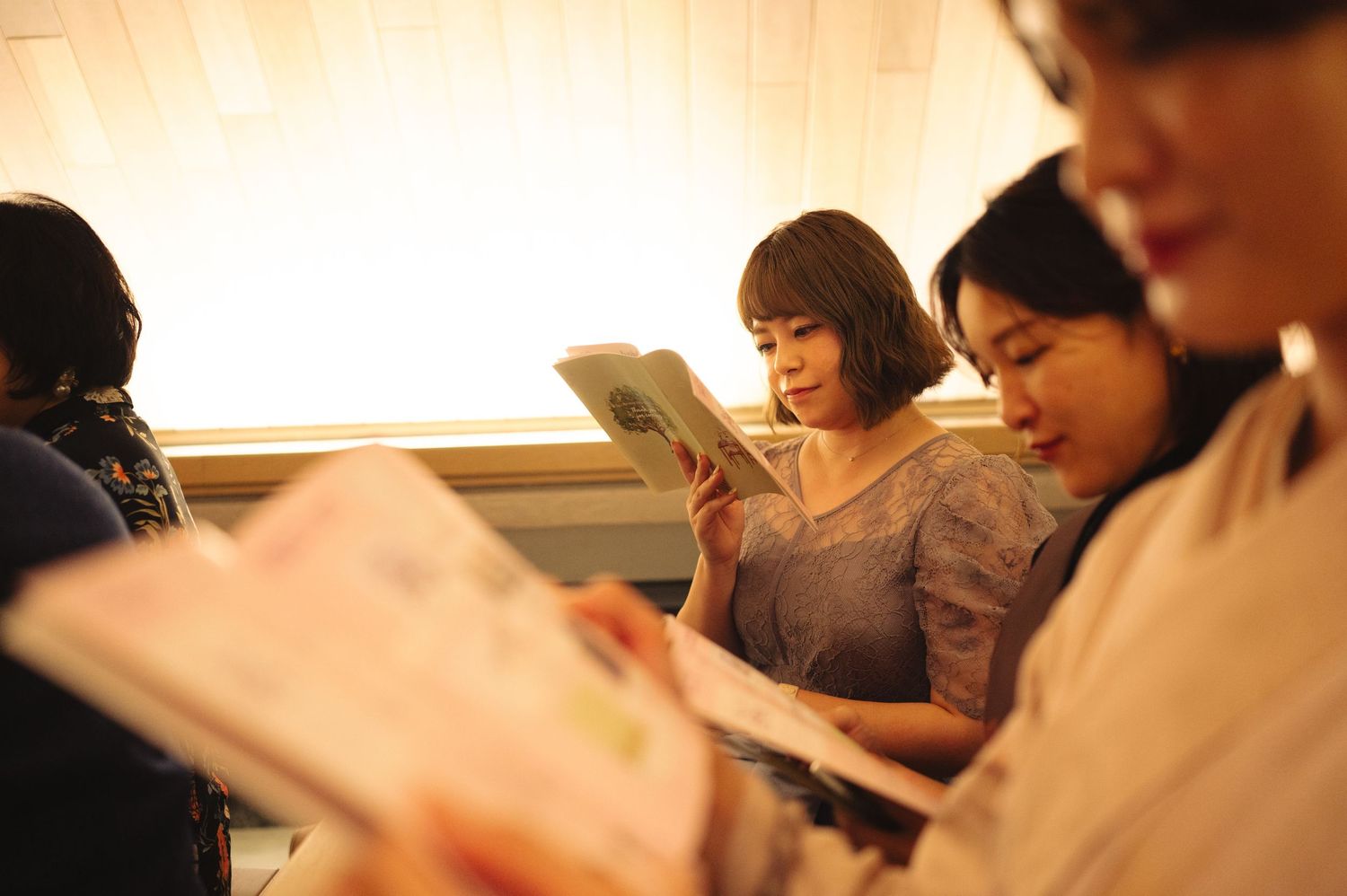 Attendees reading materials while seated in a modern venue with warm lighting.