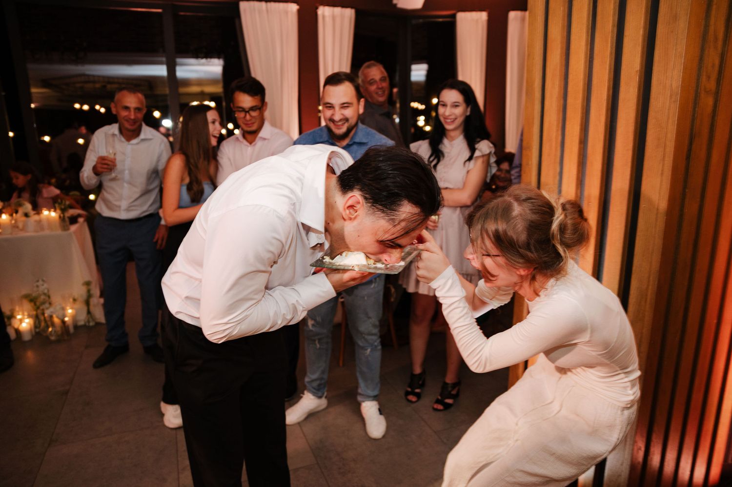 Couples dancing together at an indoor wedding reception with wooden panel walls.