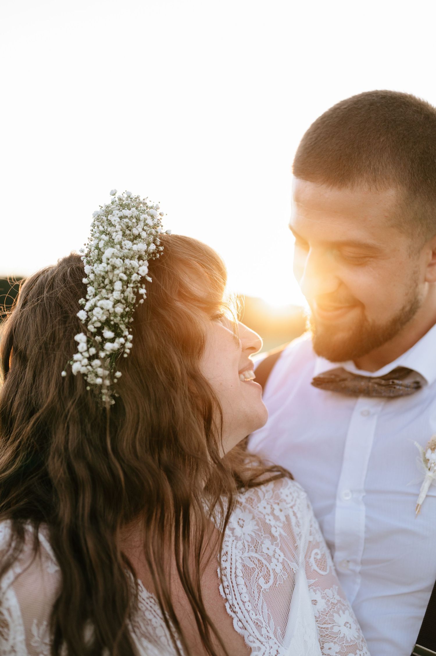 Wedding couple shares tender moment during sunset photoshoot in field.