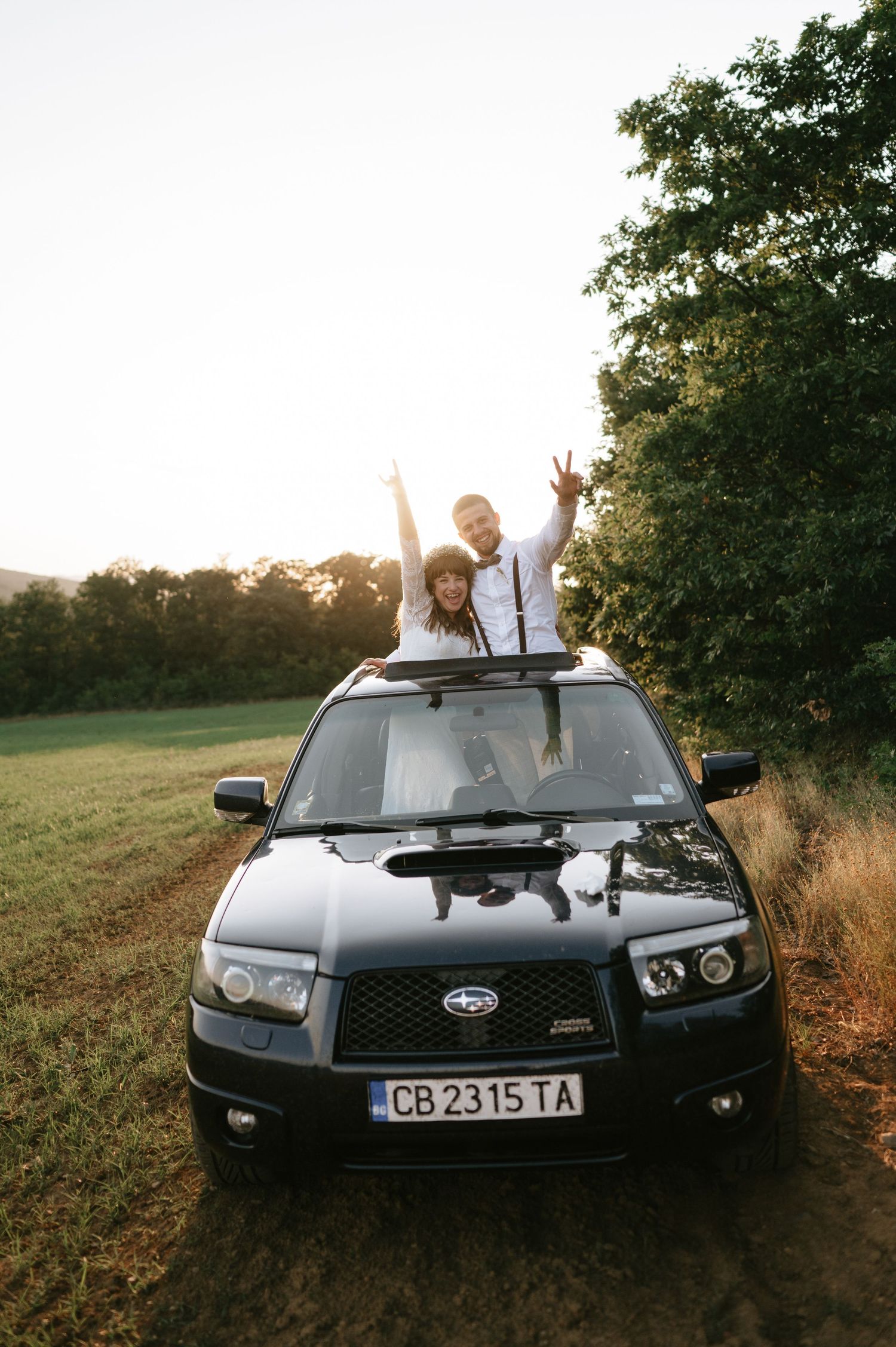 A black Subaru car parked on a dirt path during golden hour.