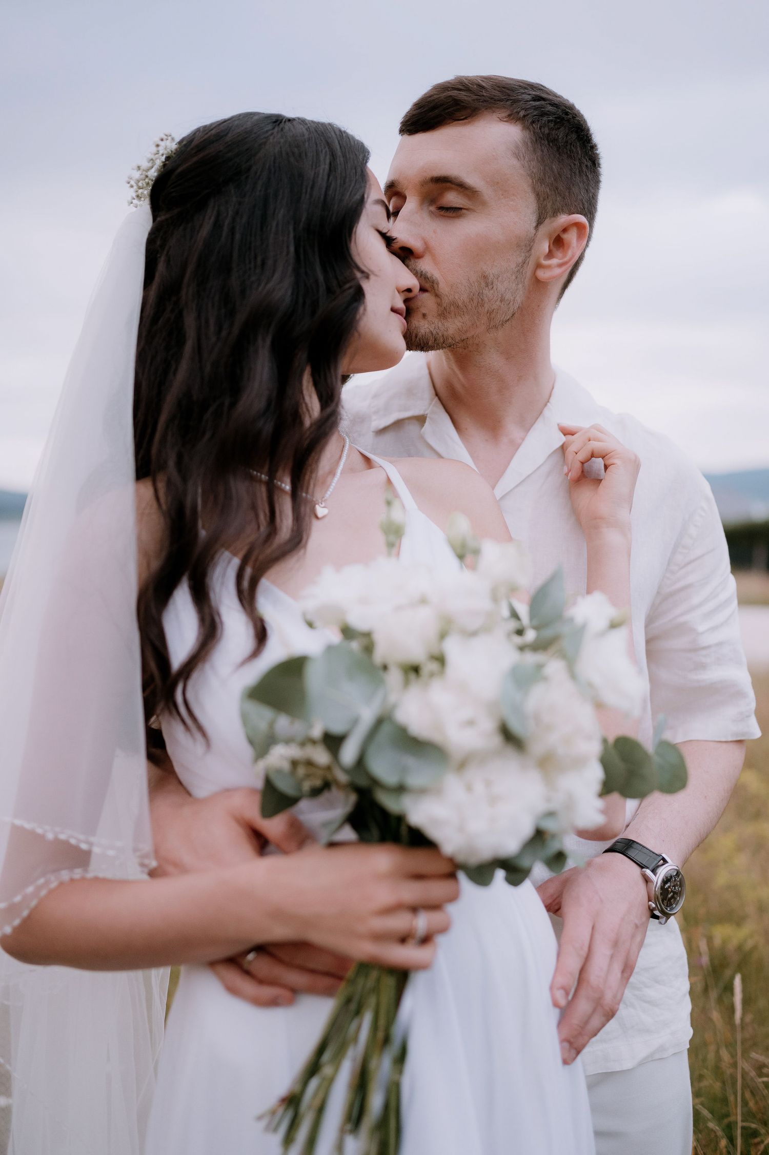 Intimate wedding photography captures tender moments between a couple in white.