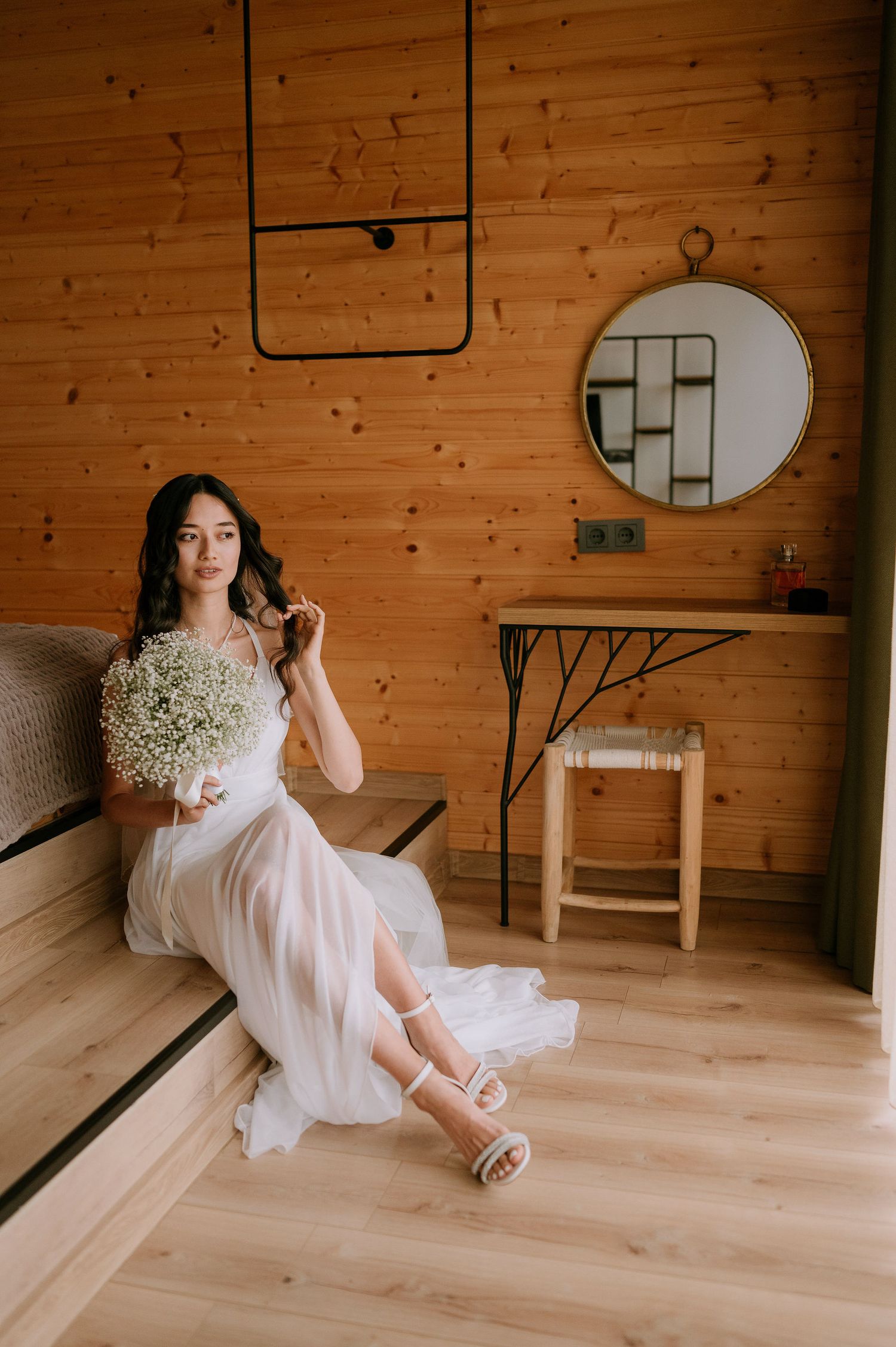 Artistic bridal photo session in rustic wooden room with natural light and white dress.