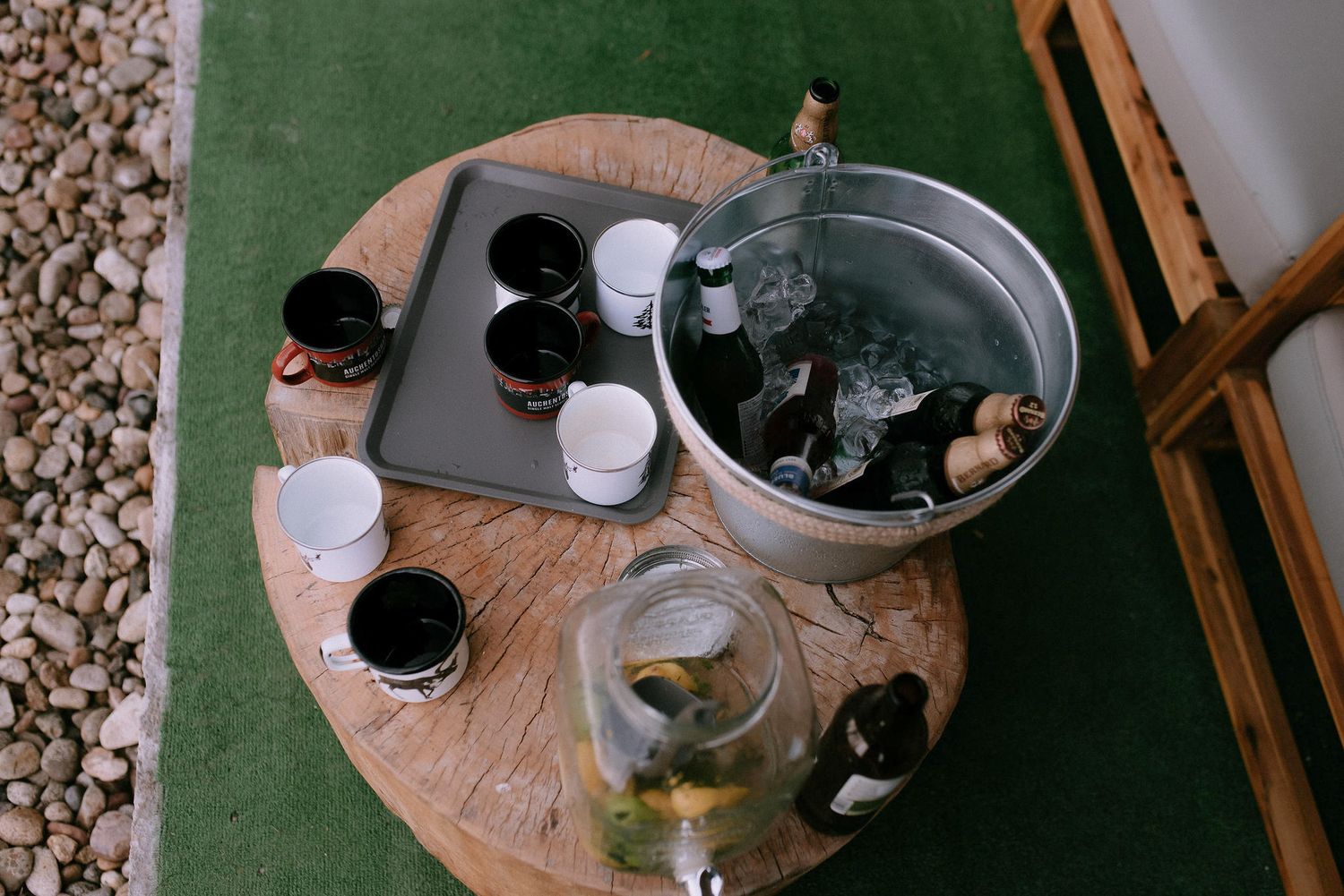 Drinks and glasses arranged on wooden table at outdoor reception.