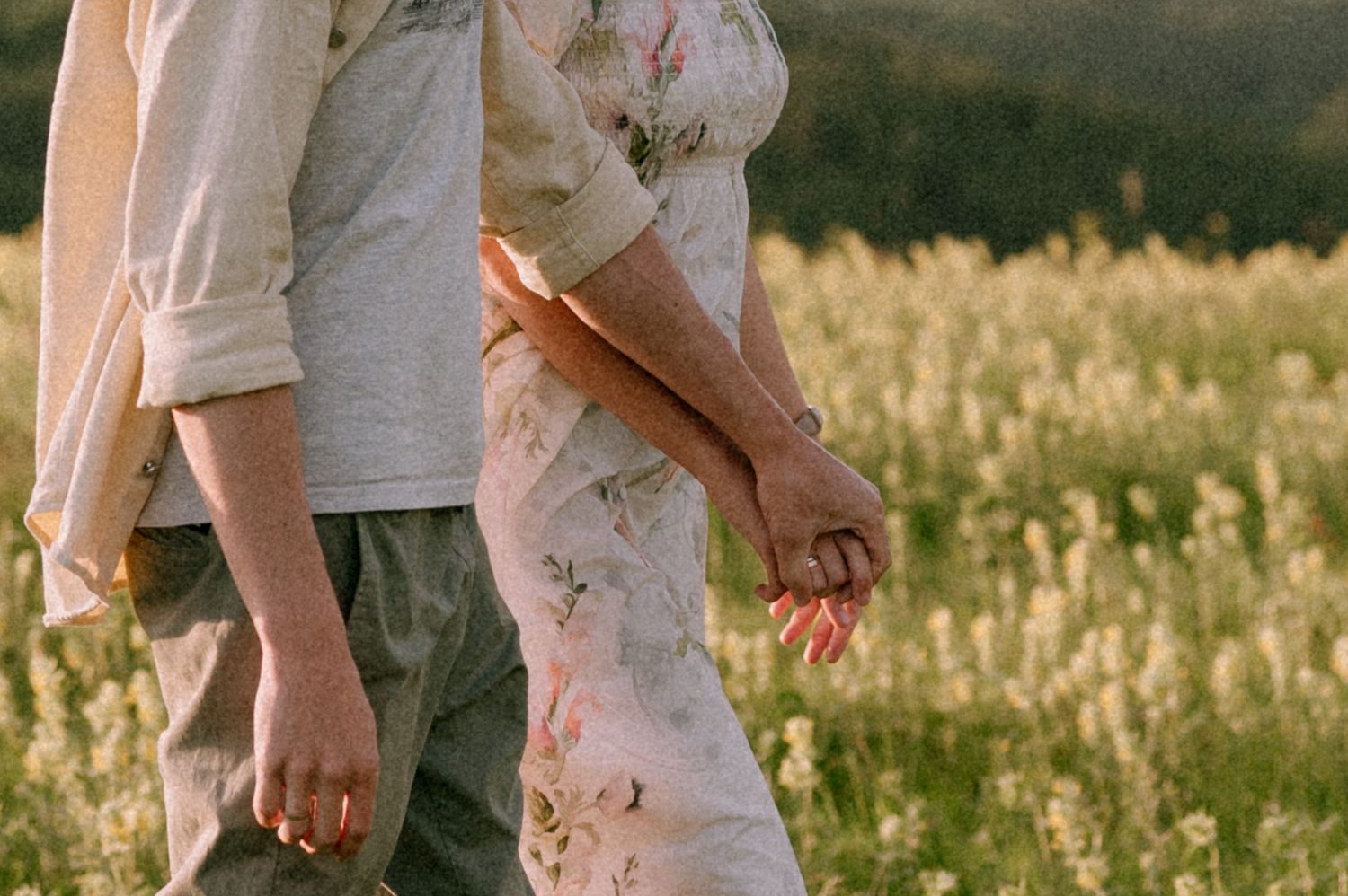 Close-up of two people standing together in a summer field at sunset.