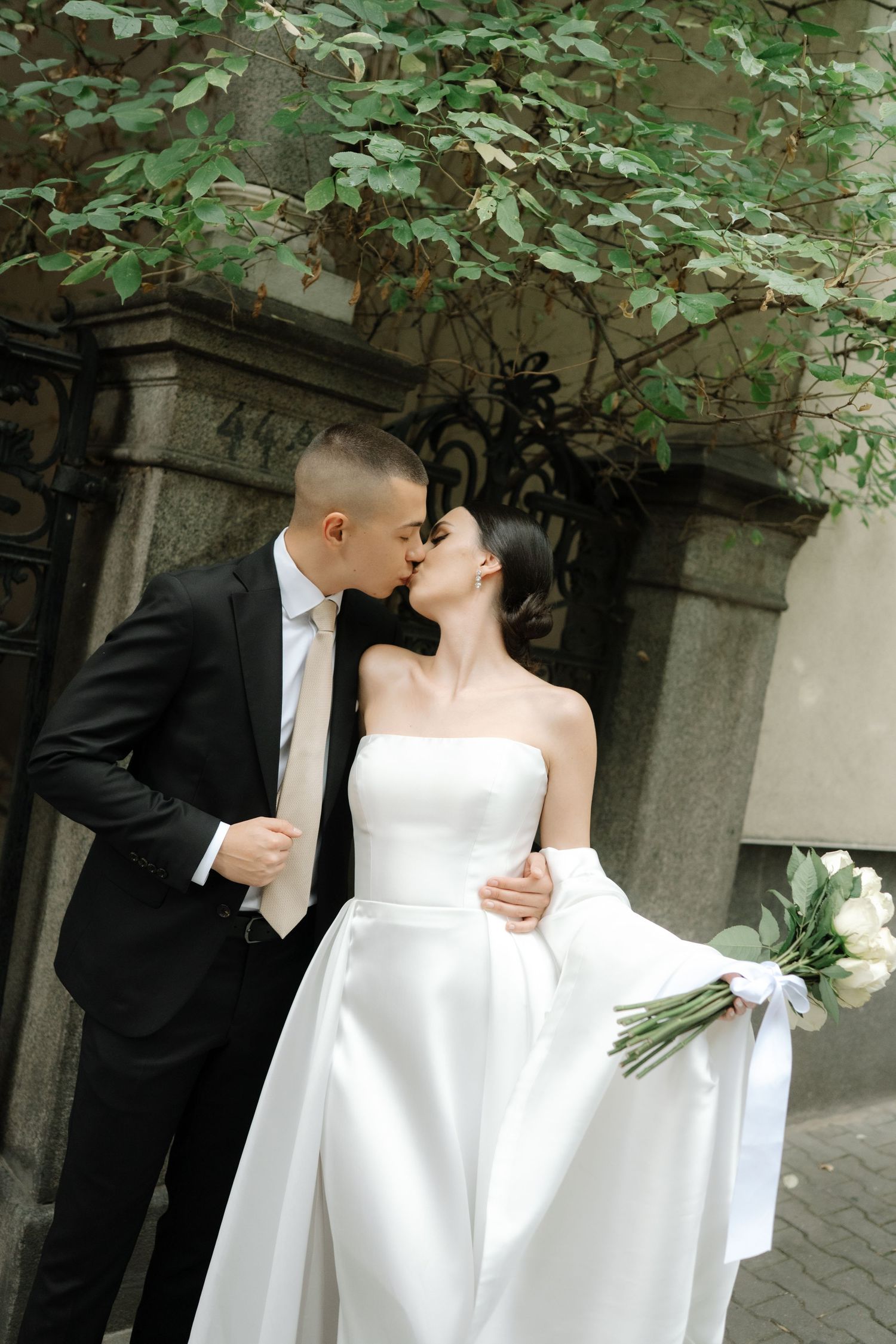 A romantic sequence of wedding photos showing a couple in formal attire sharing tender moments under green foliage.
