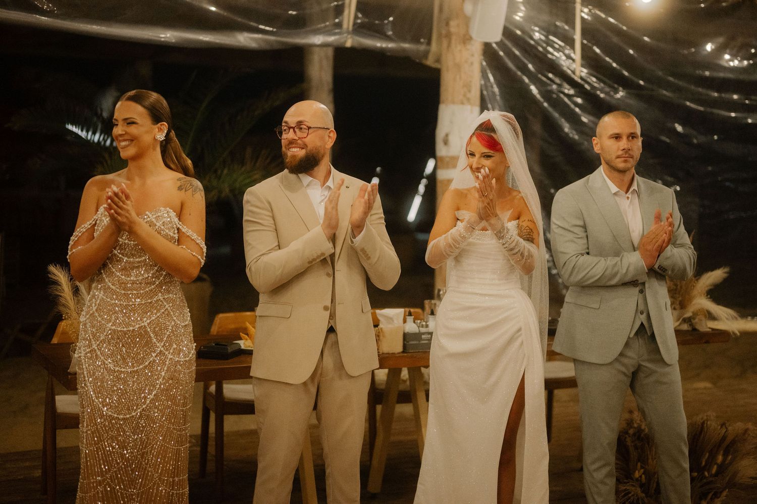 Wedding celebration under string lights with party members applauding during evening reception.