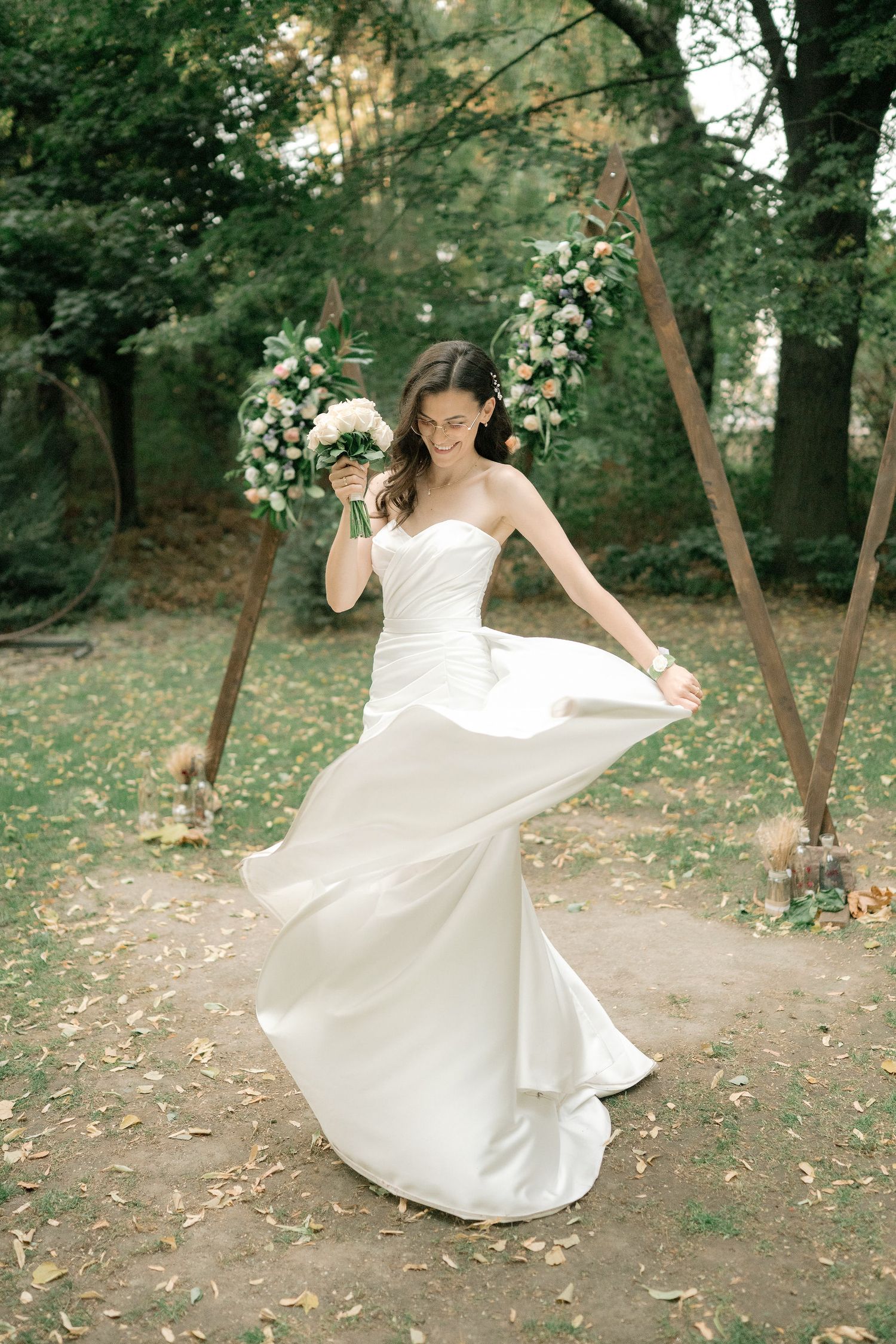 A flowing white wedding dress twirls in motion against a romantic garden backdrop with floral arch decorations.