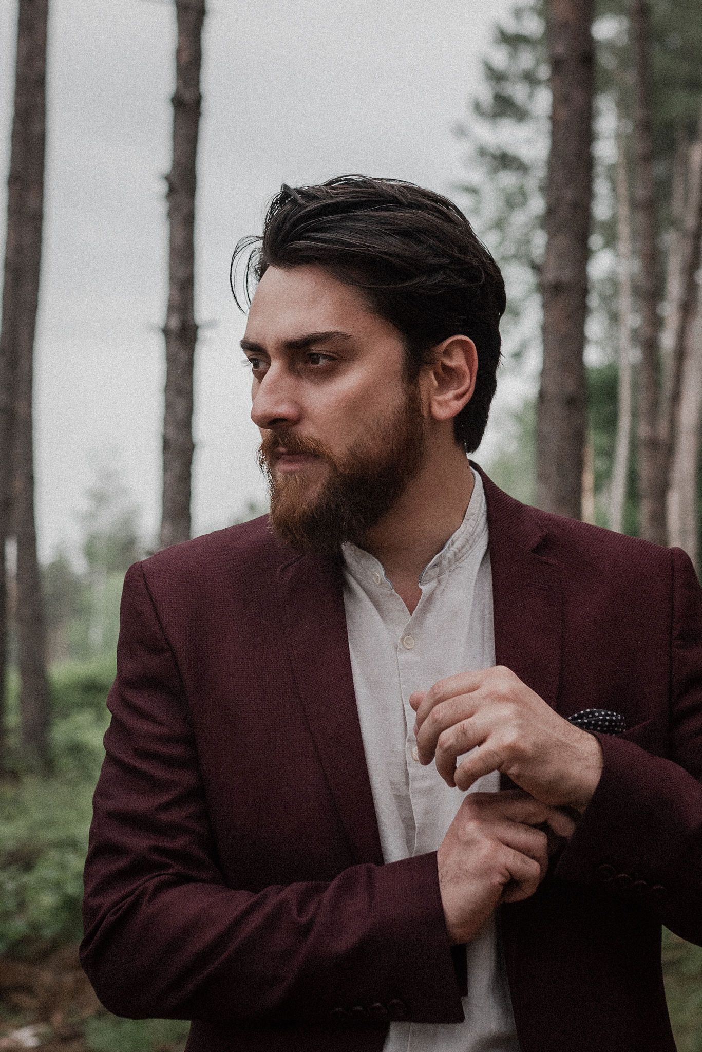 A person in a burgundy suit jacket and white shirt poses dramatically in a forest setting across multiple frames.