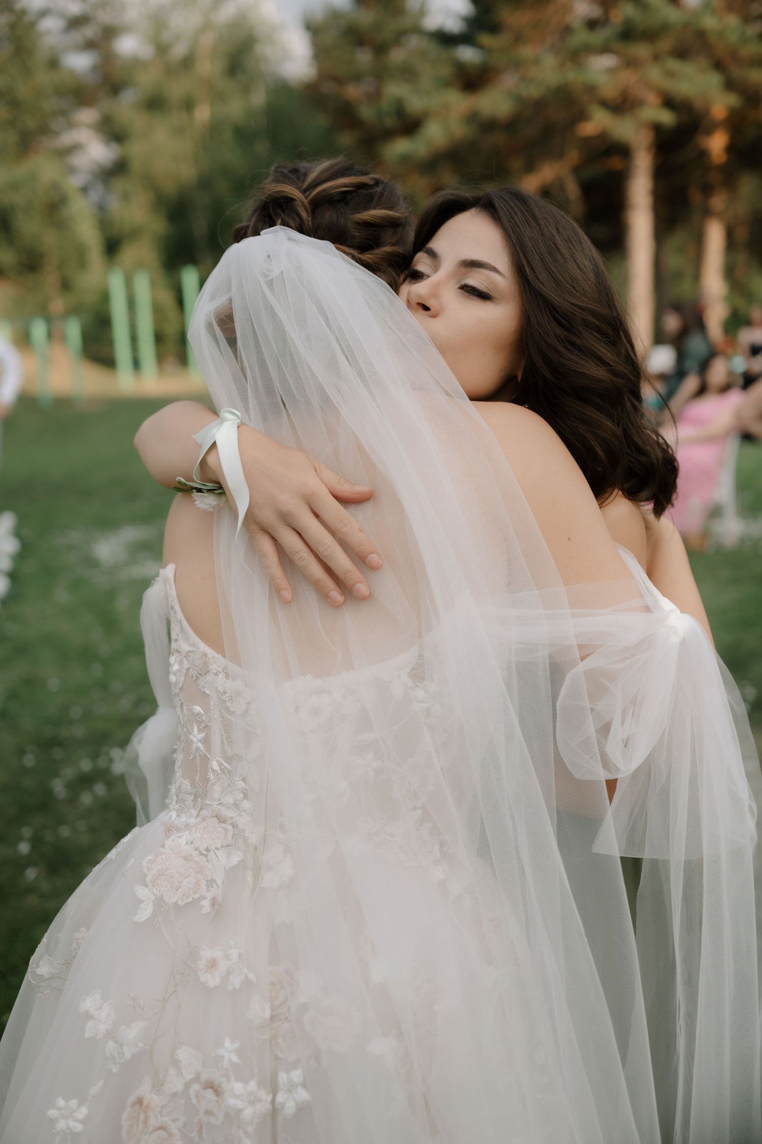 Intimate wedding couple shares tender embraces and kisses under flowing white veil in outdoor garden setting.