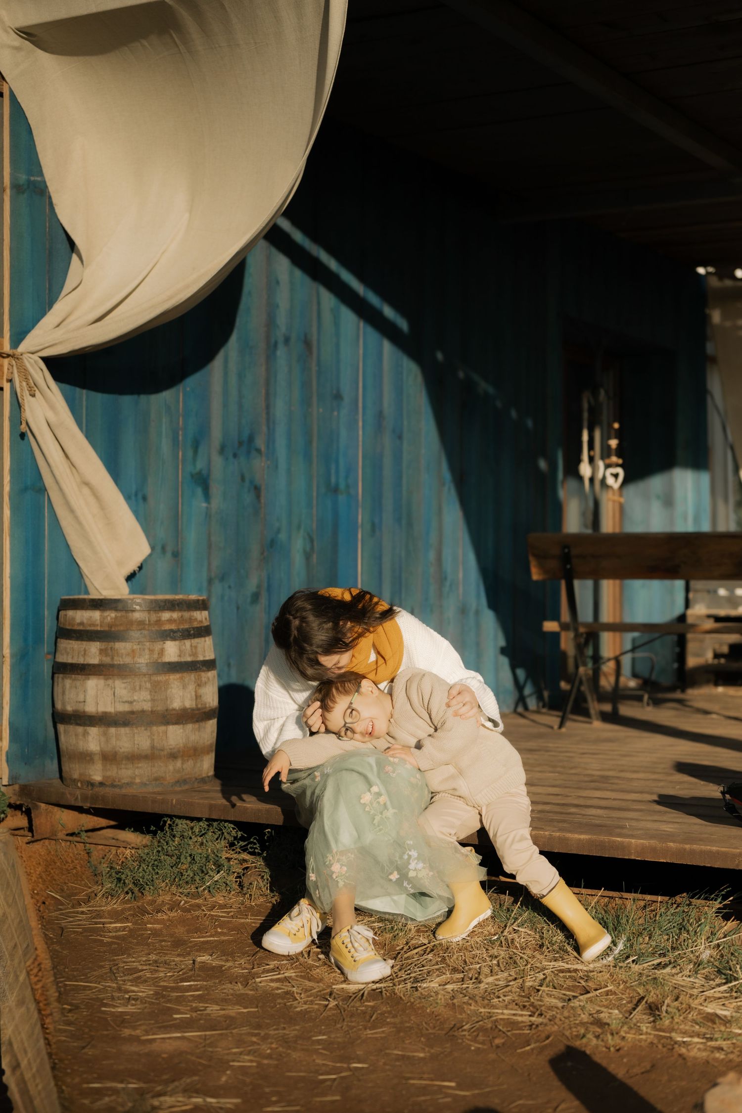 A series of photos showing someone in white clothing resting against wooden barrels on a rustic porch.