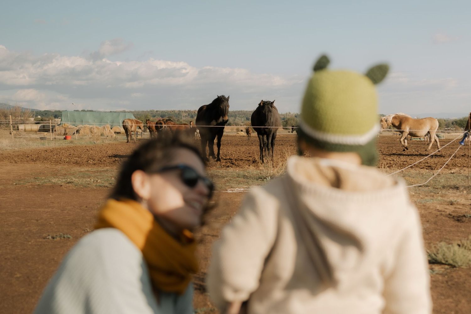 A group of people riding camels across a desert landscape under a bright blue sky.