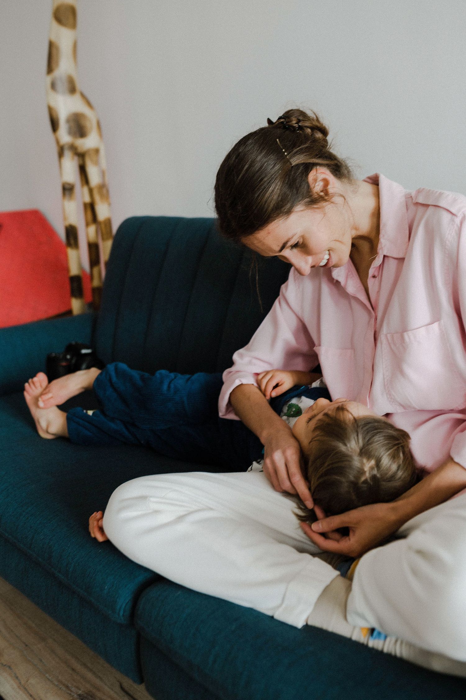 A tender moment shared between parent and child relaxing together on a navy blue couch with a giraffe toy in background.