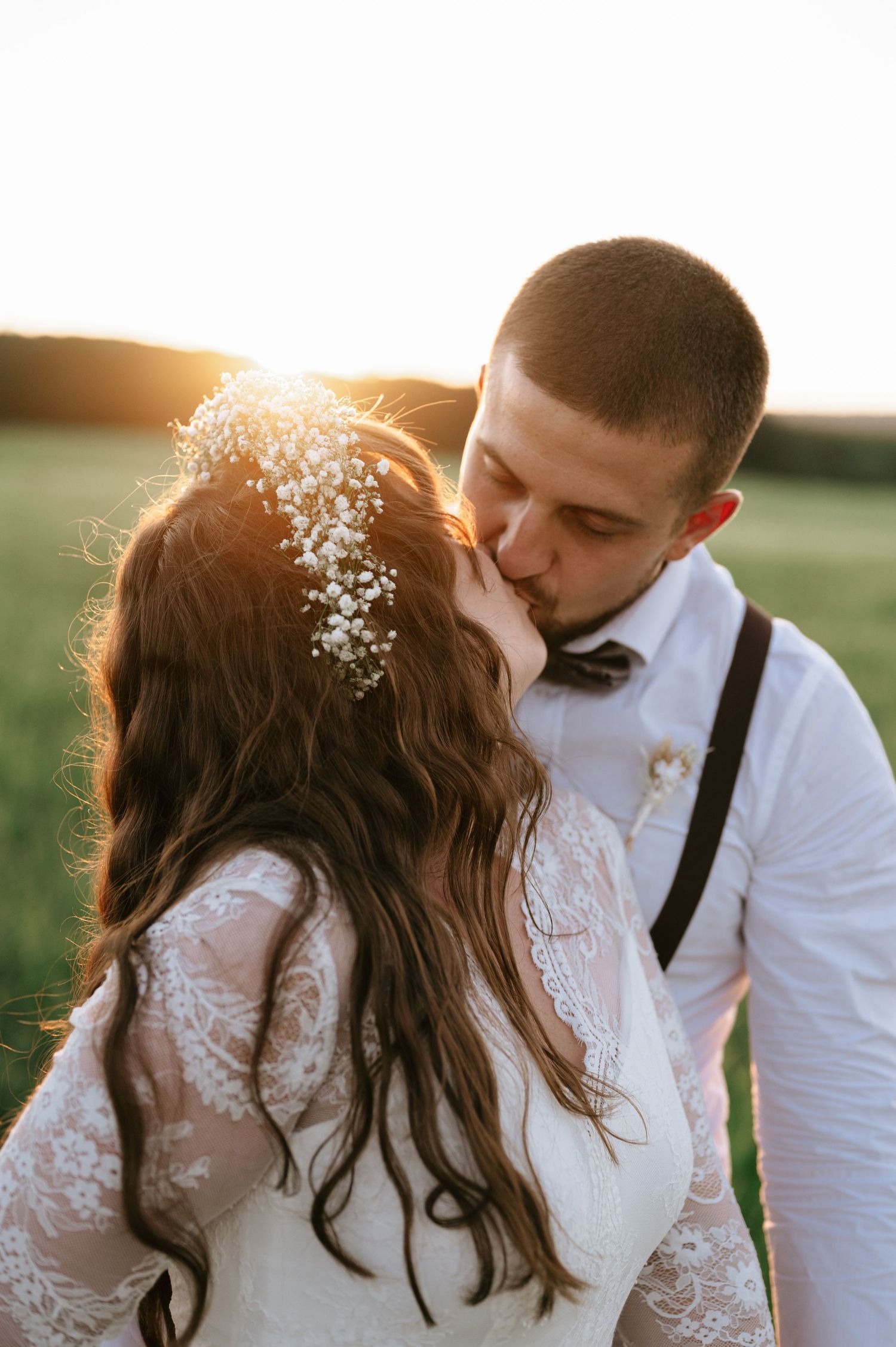 Intimate wedding couple portrait with golden sunlight in a meadow.
