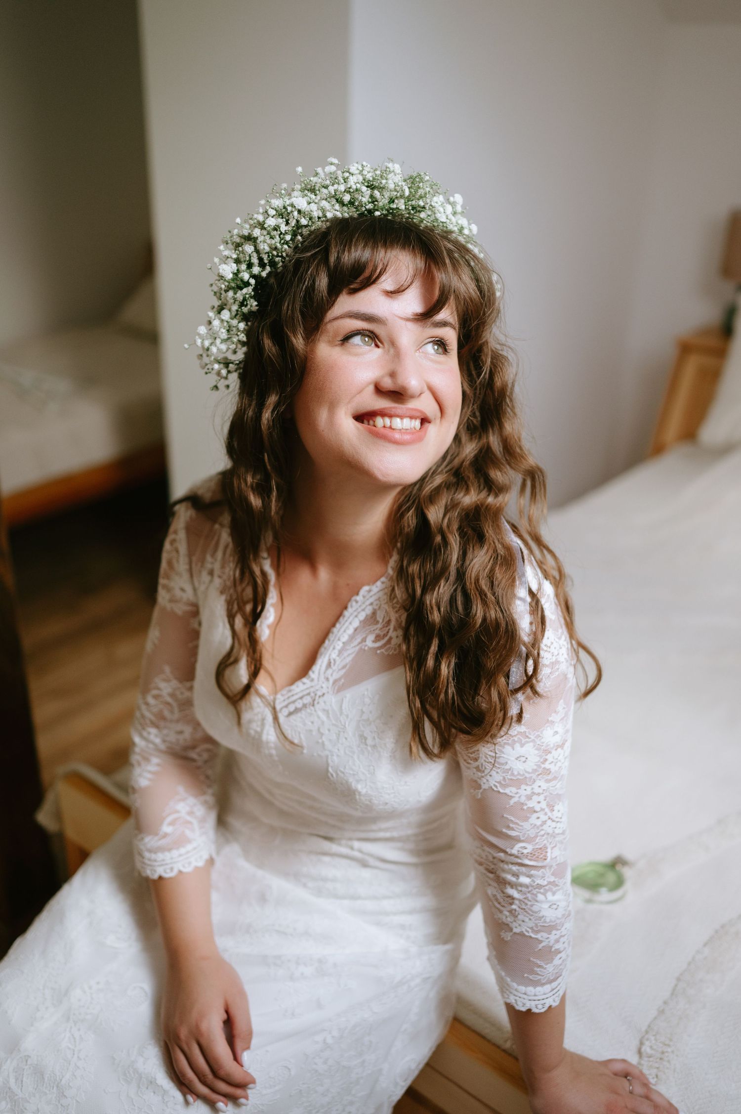 A delicate lace wedding dress with three-quarter sleeves and baby's breath crown in a natural light setting.