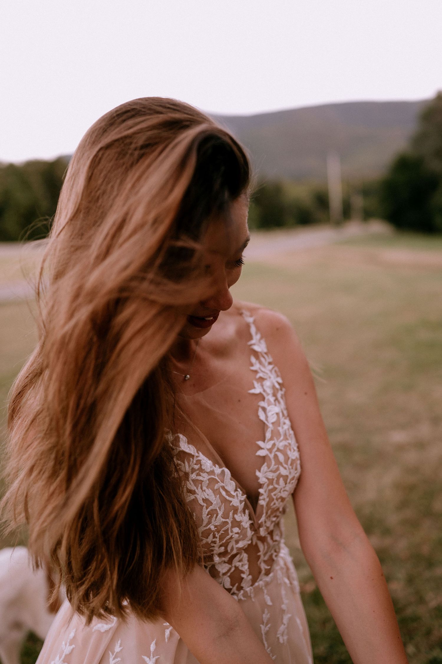 Person in delicate lace dress poses in a field during golden hour.