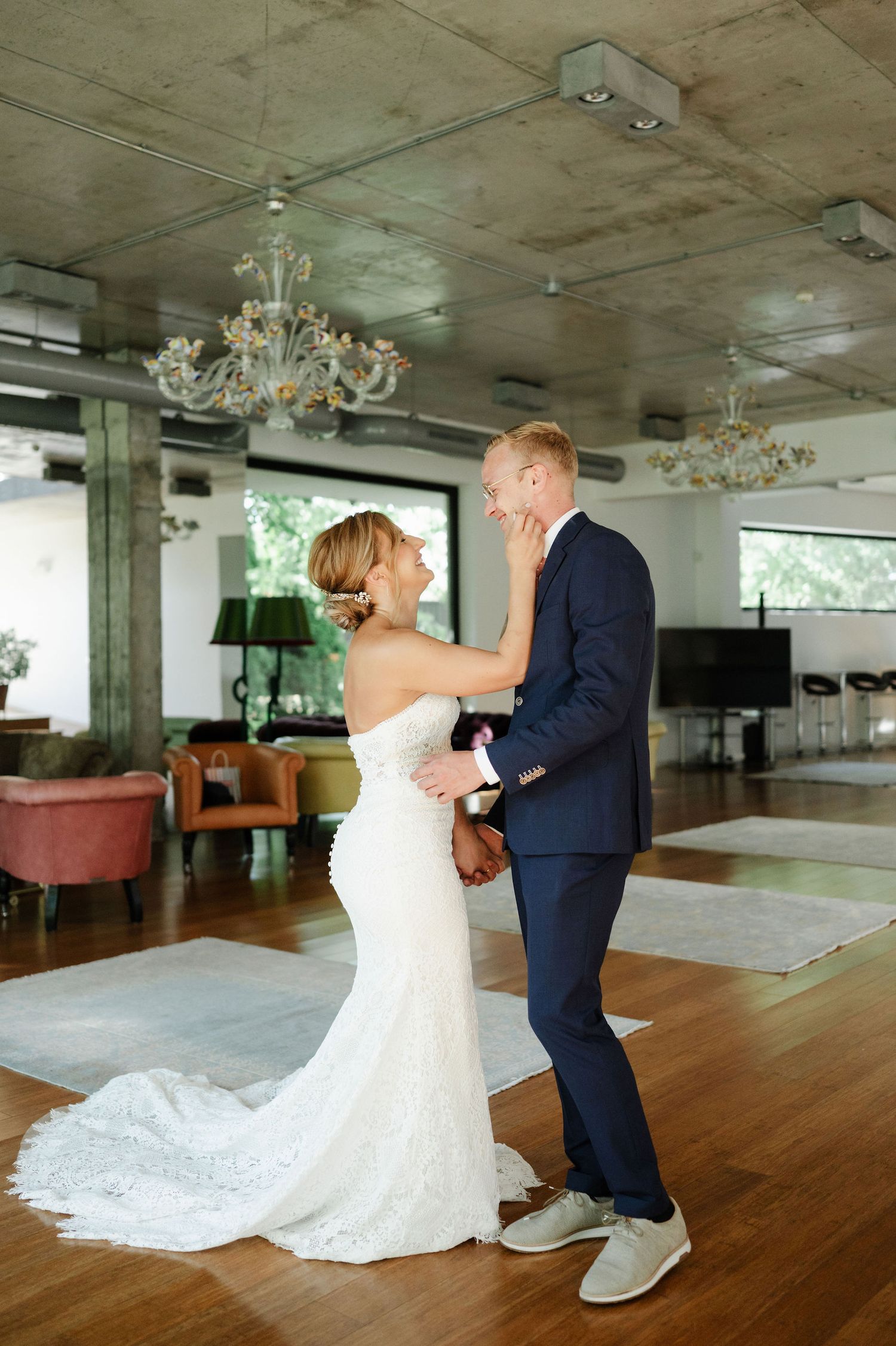 A couple shares a dance in their wedding attire beneath crystal chandeliers.
