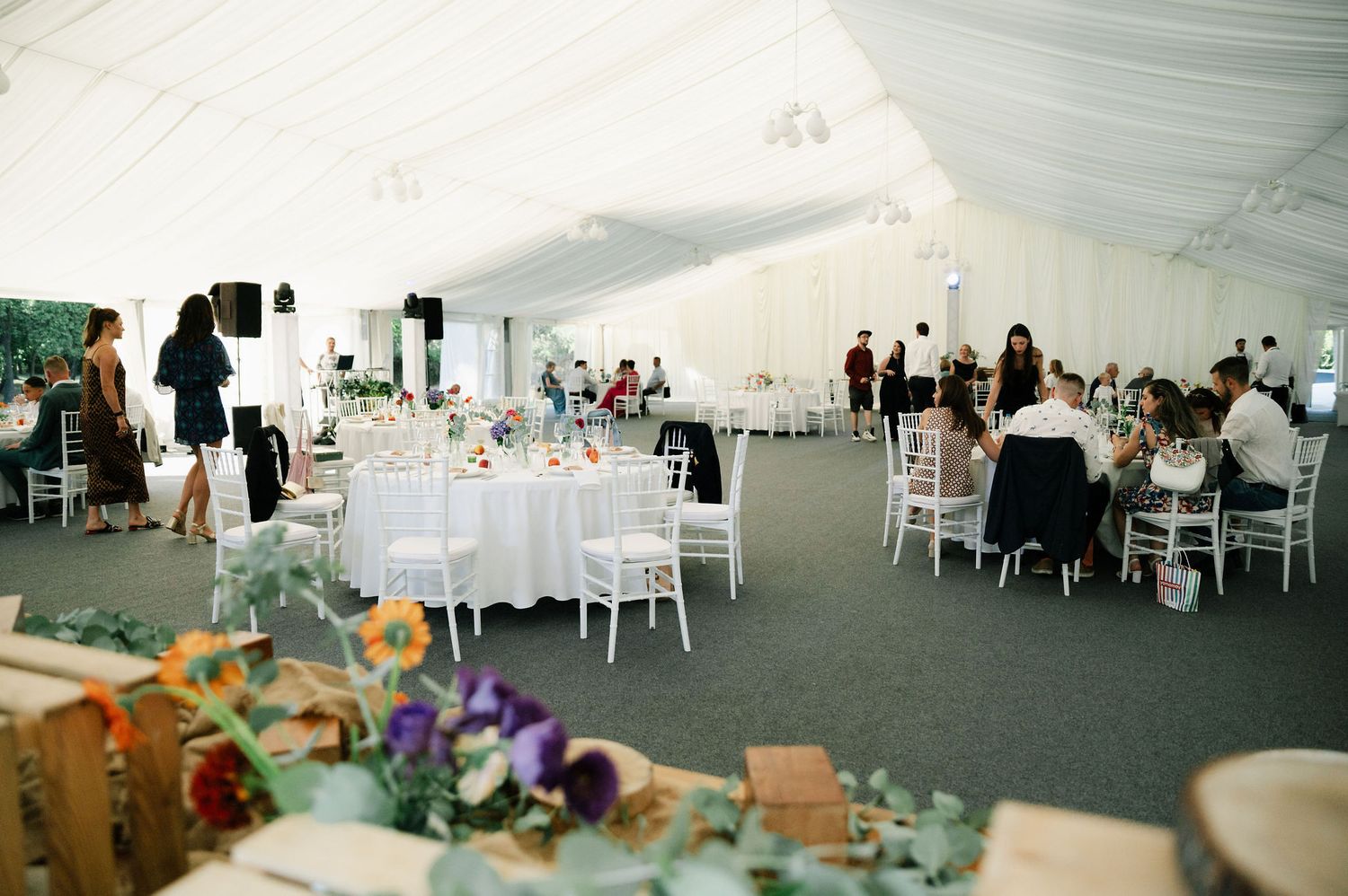 Panoramic view of wedding reception space with white chairs and tables under tent canopy.