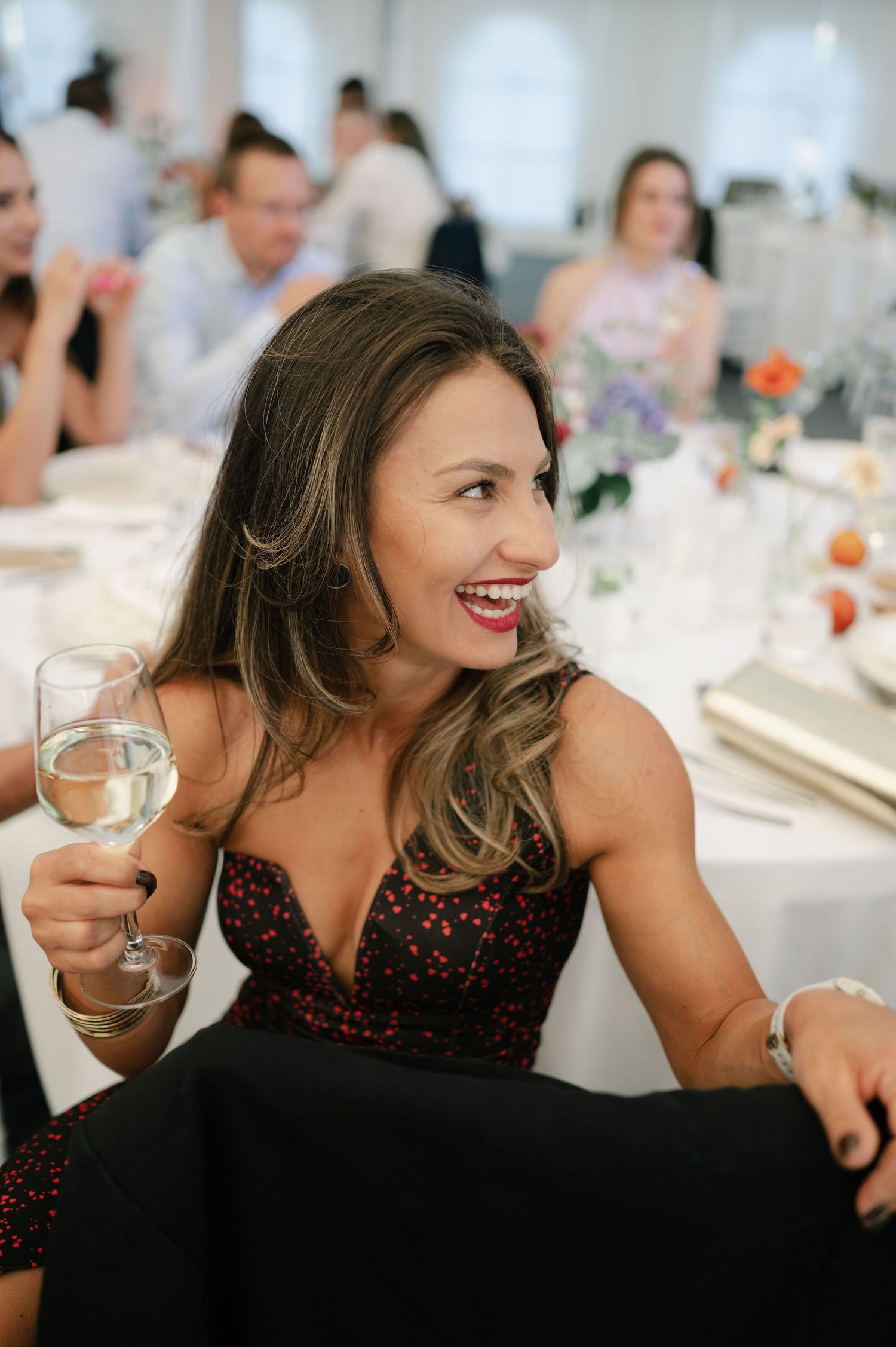 Guest in a dark dress enjoying wine and conversation at a wedding reception.