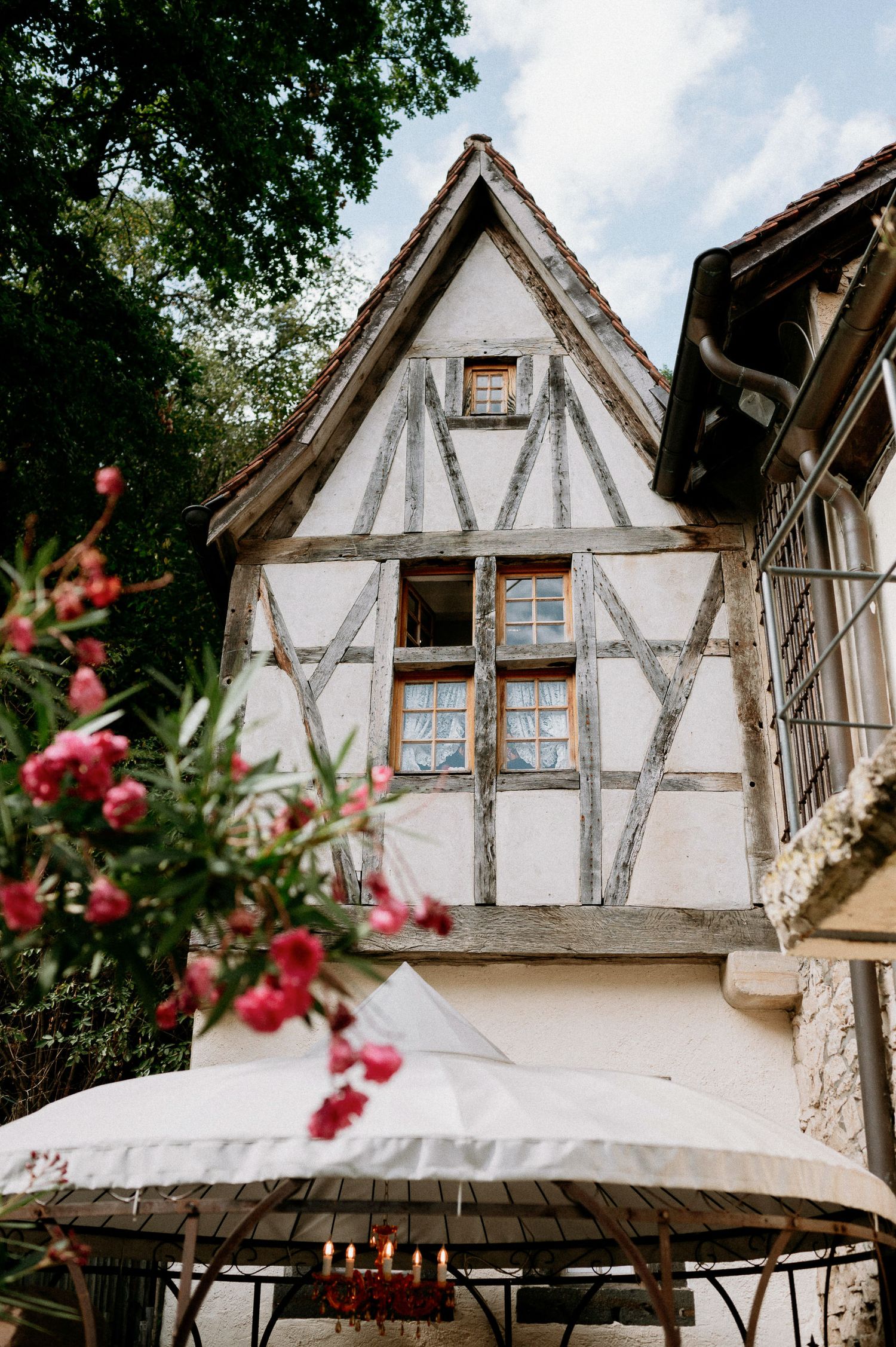 Traditional Tudor-style house exterior with timber framing and white plaster walls under sunny skies.