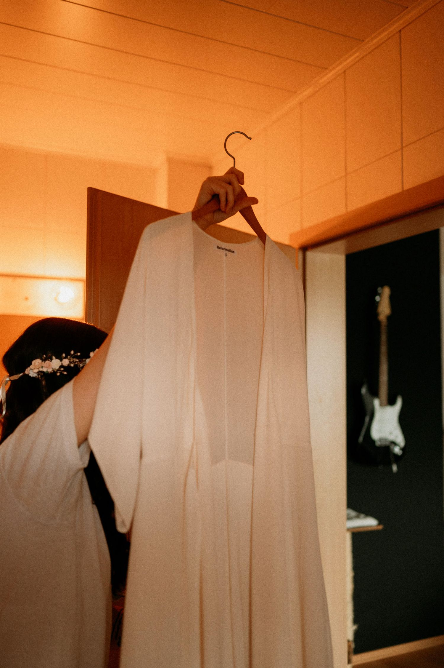 White garments hanging on hangers against an orange-tinted wall.