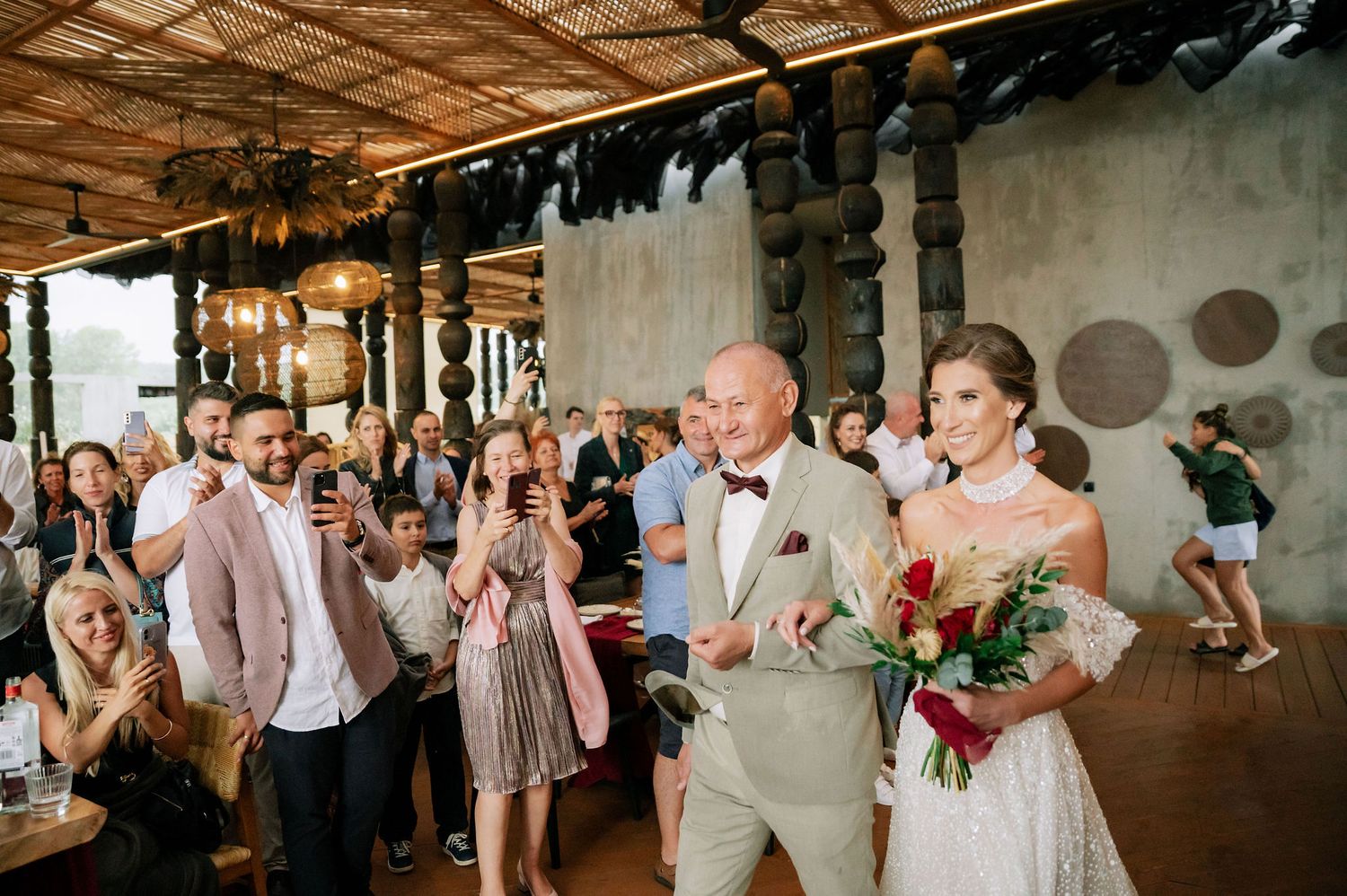 Wedding reception crowd gathered in an industrial-style venue with wooden ceiling details.