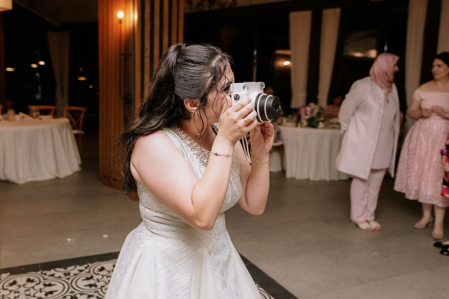 Wedding party dancing and celebrating in a warmly lit indoor reception venue.