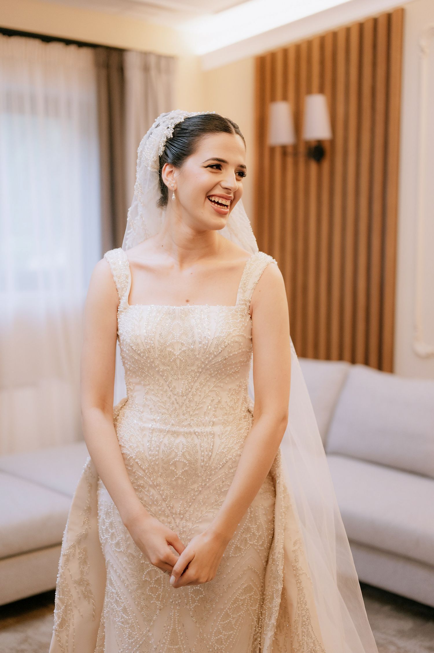 A radiant bride wearing a sparkly white wedding gown smiles during her preparation moments.