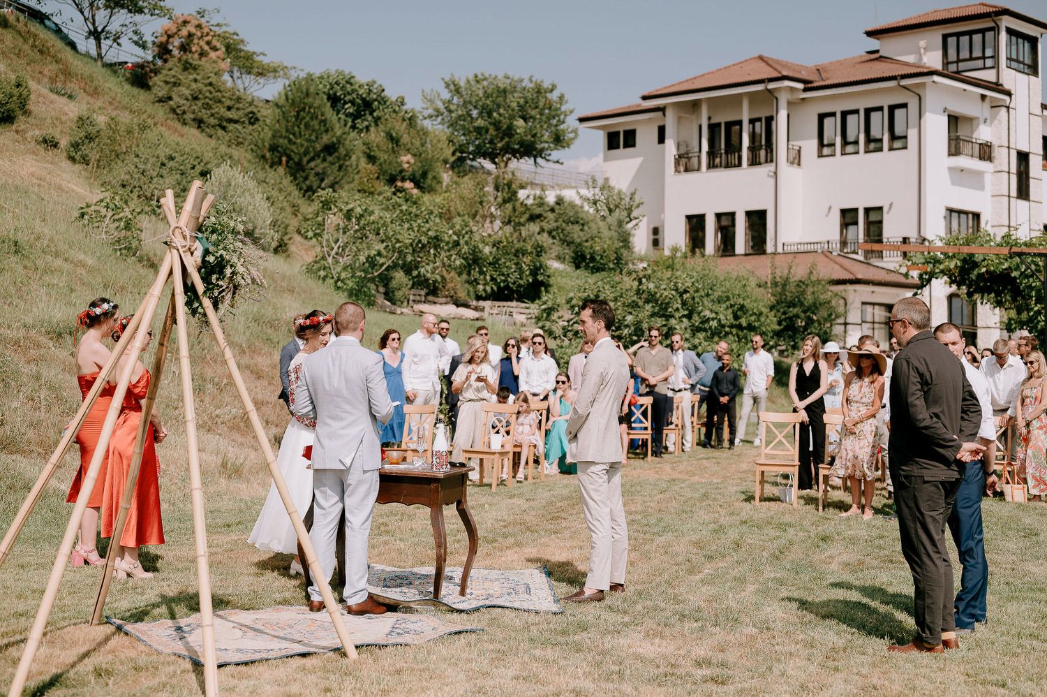 Outdoor wedding ceremony setup with wooden arch and chairs against a scenic mountain backdrop.