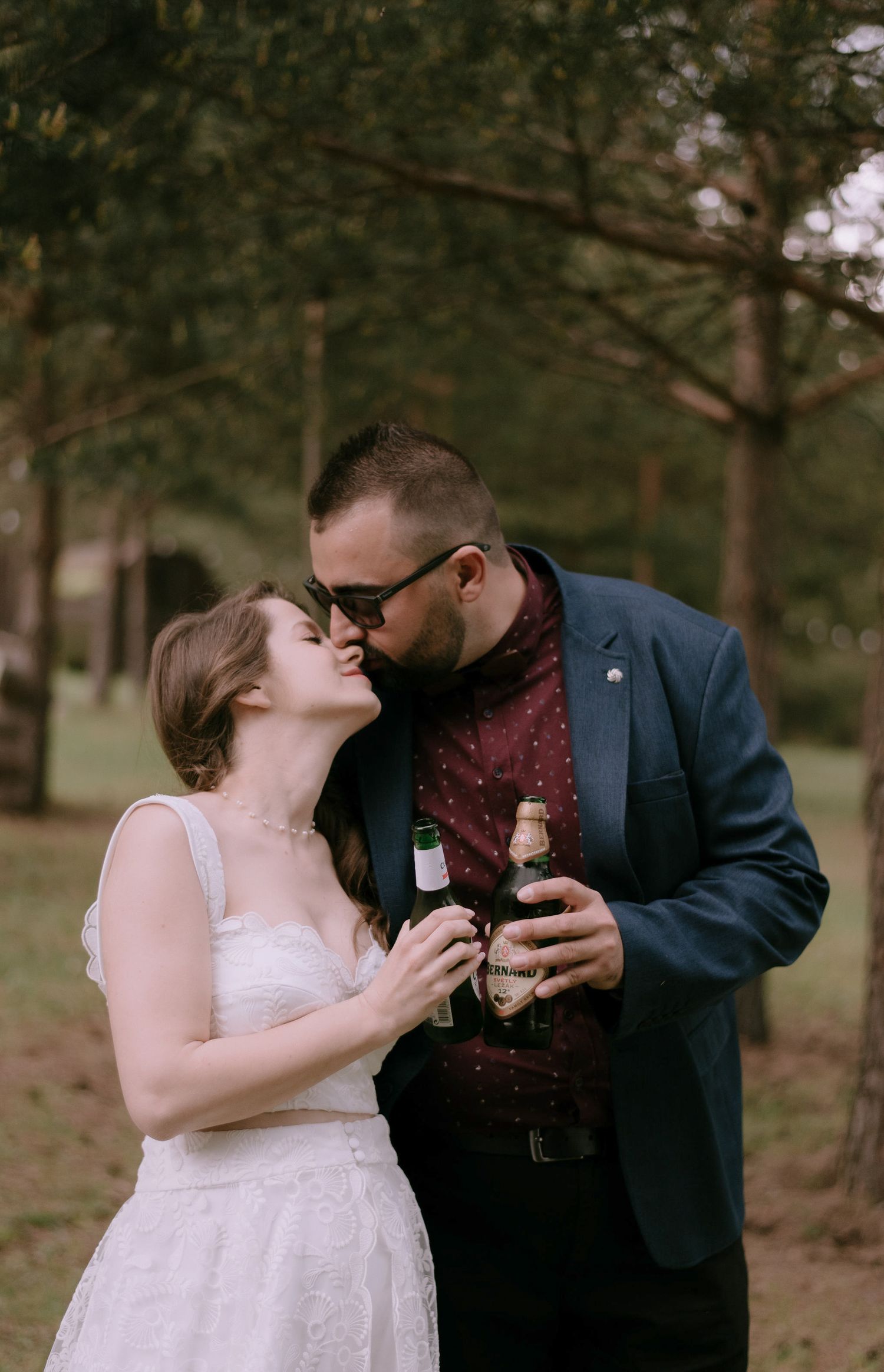A couple shares intimate moments while holding beverages during an outdoor photoshoot.