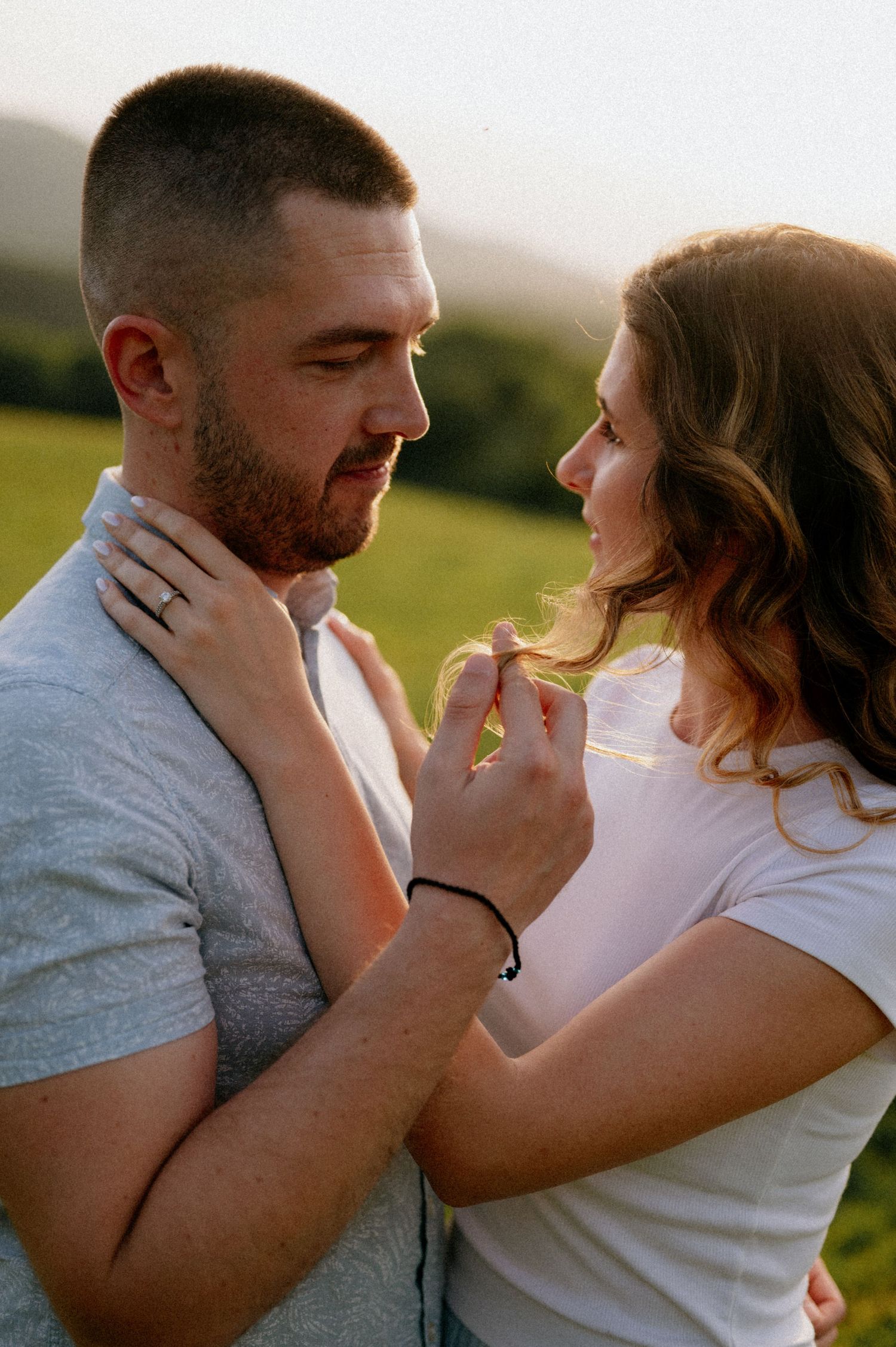 Two people share an intimate moment while holding each other's faces tenderly in the evening light.