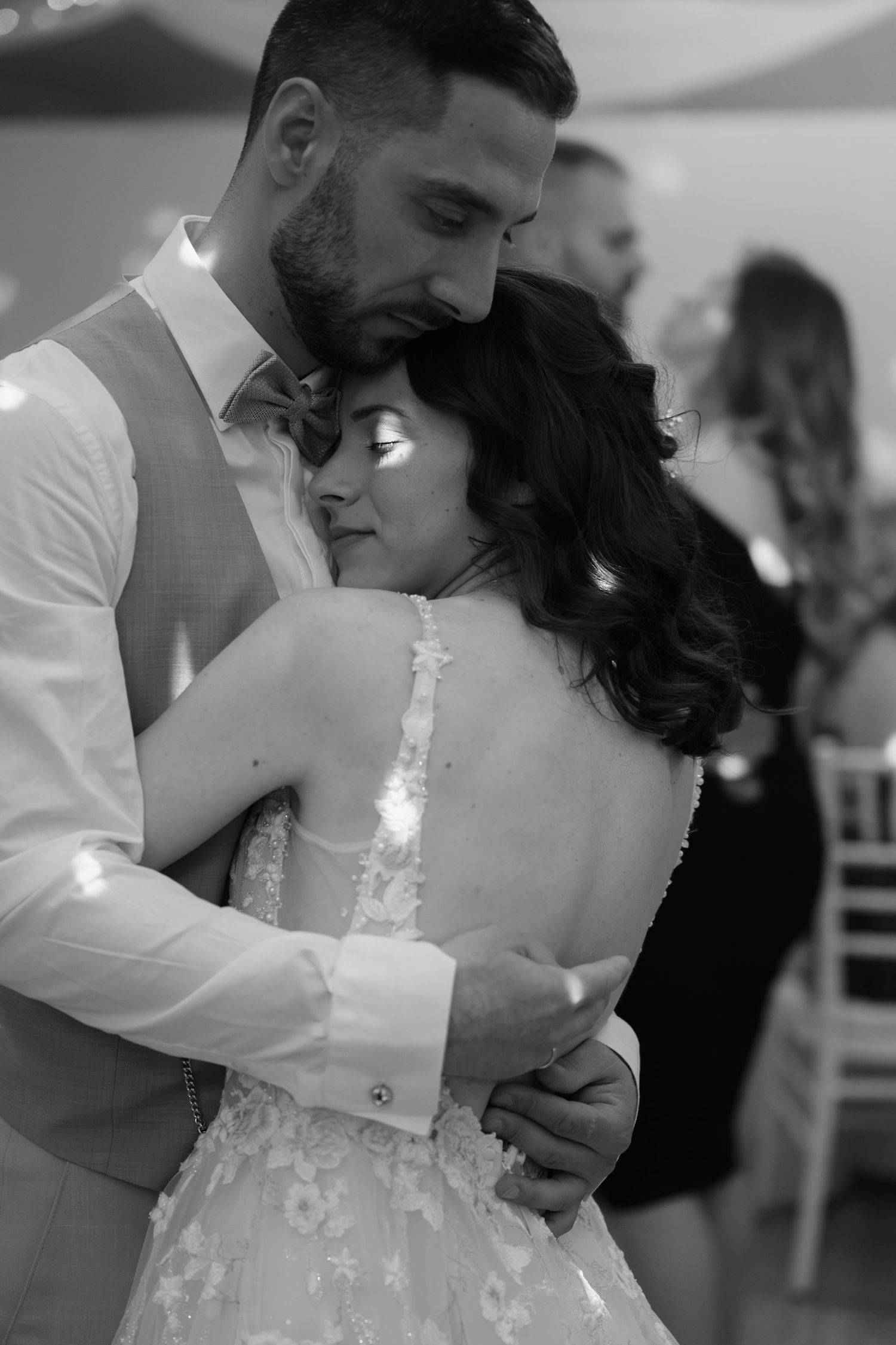 Black and white photo of a bride and groom sharing an intimate first dance embrace at their wedding reception.