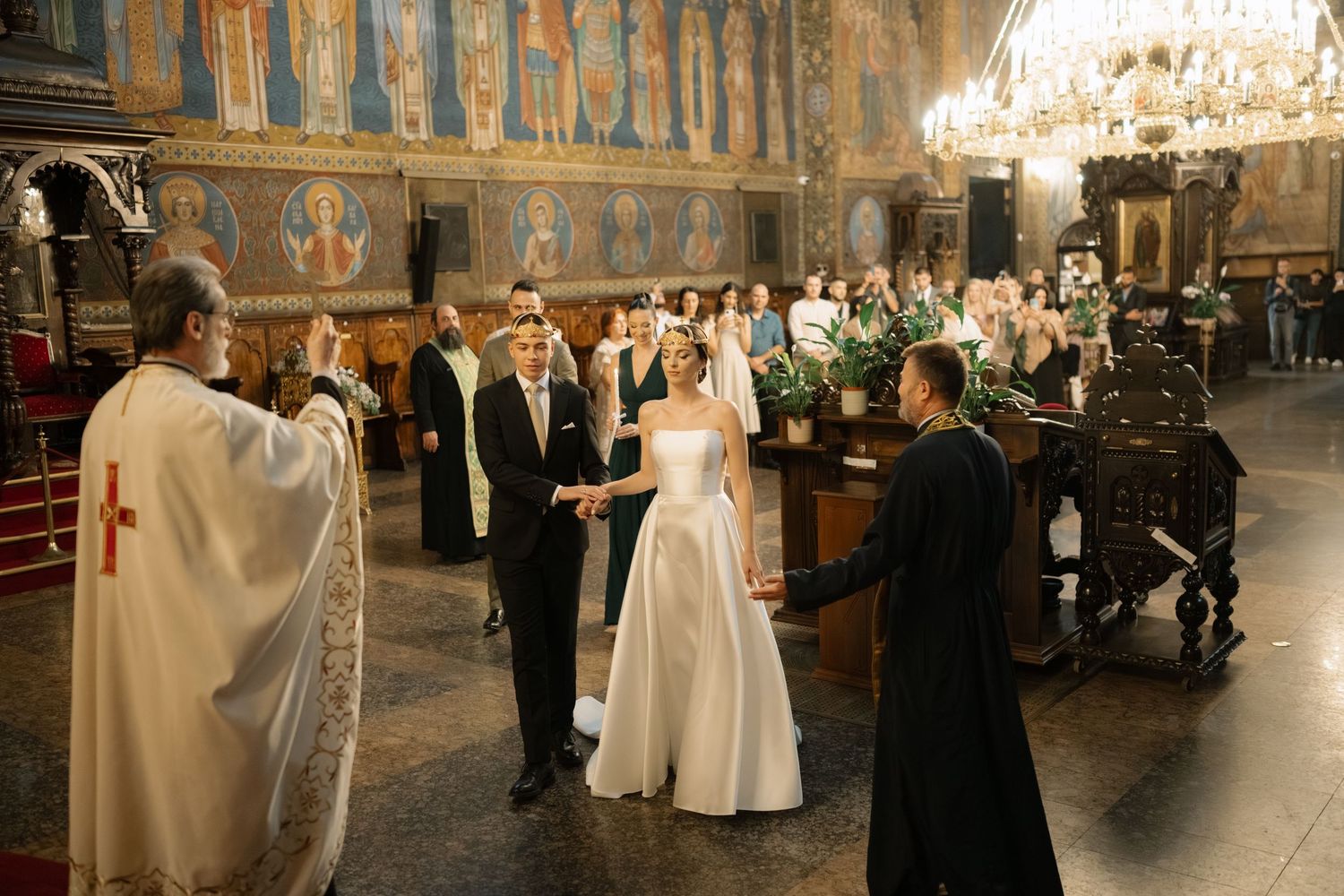 Wedding ceremony taking place in an ornate church with guests seated in wooden pews and traditional decor.