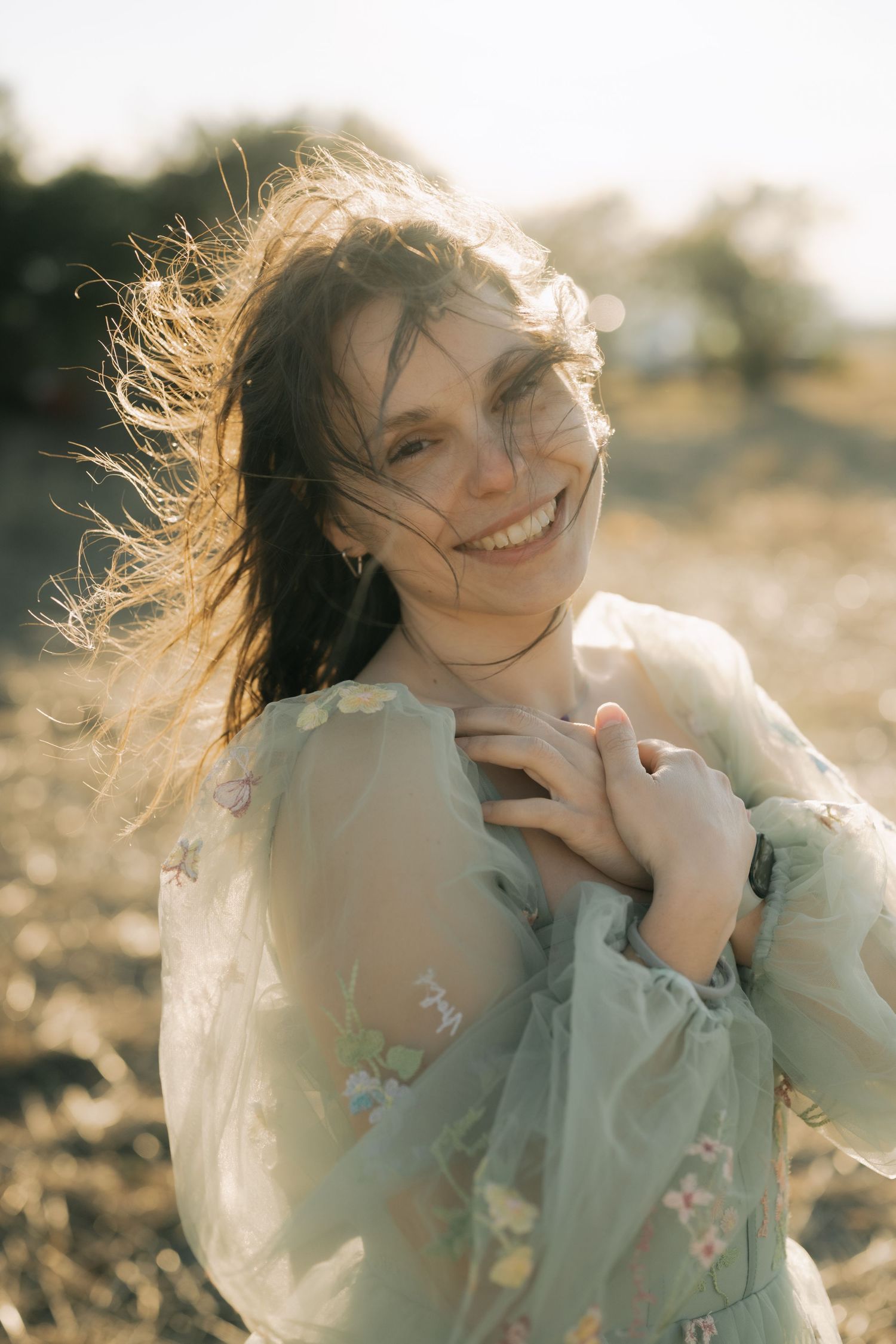 Dreamy sunlit portrait series showing joyful expressions and windswept hair in a mint green floral dress.