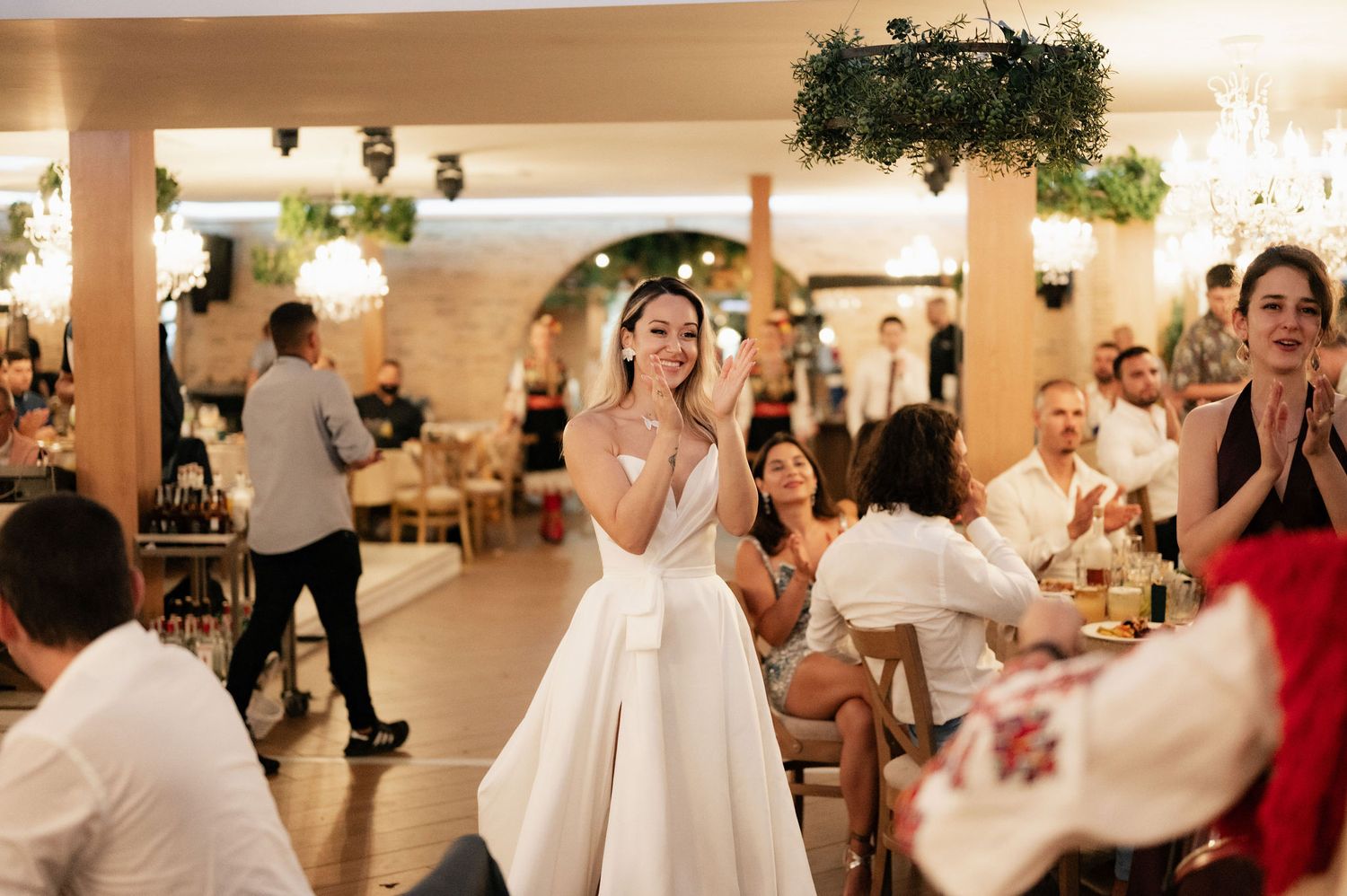 Wedding reception guests dancing and celebrating on the dance floor at an elegant indoor venue with decorative lighting.