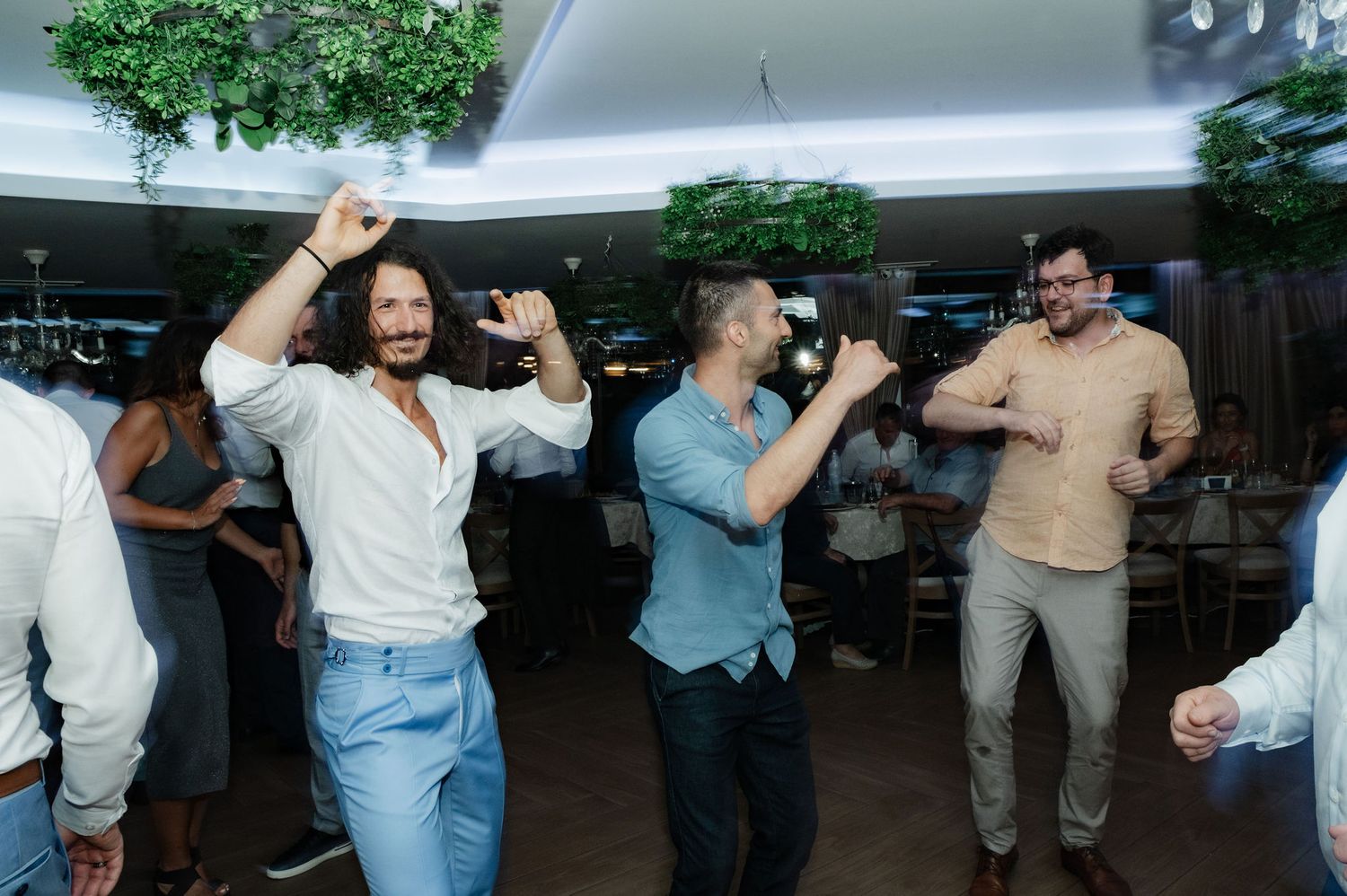 Guests dancing together at an outdoor event under a white tent.