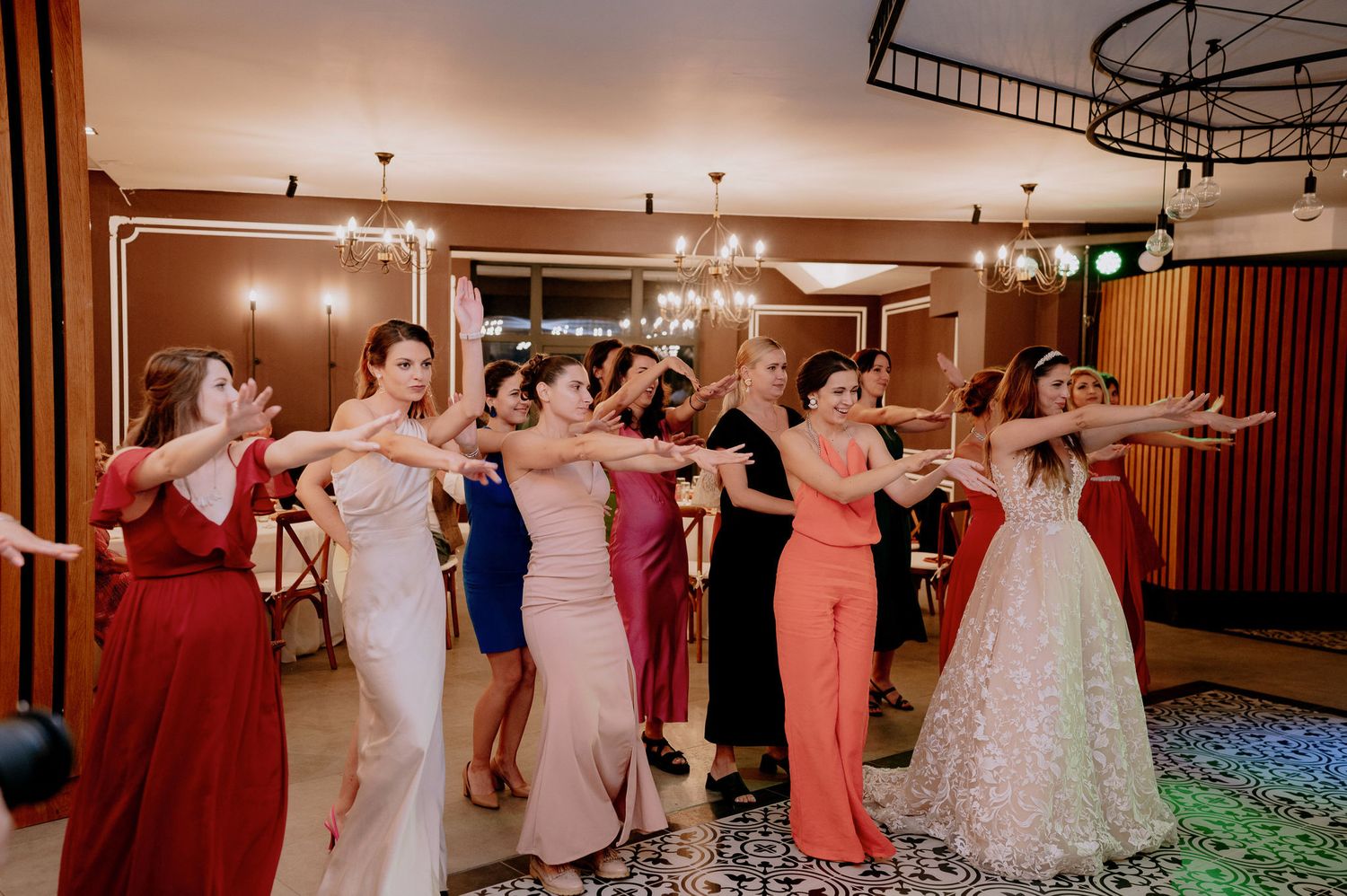 Wedding party dances together in a ballroom during reception with hands raised in celebration.