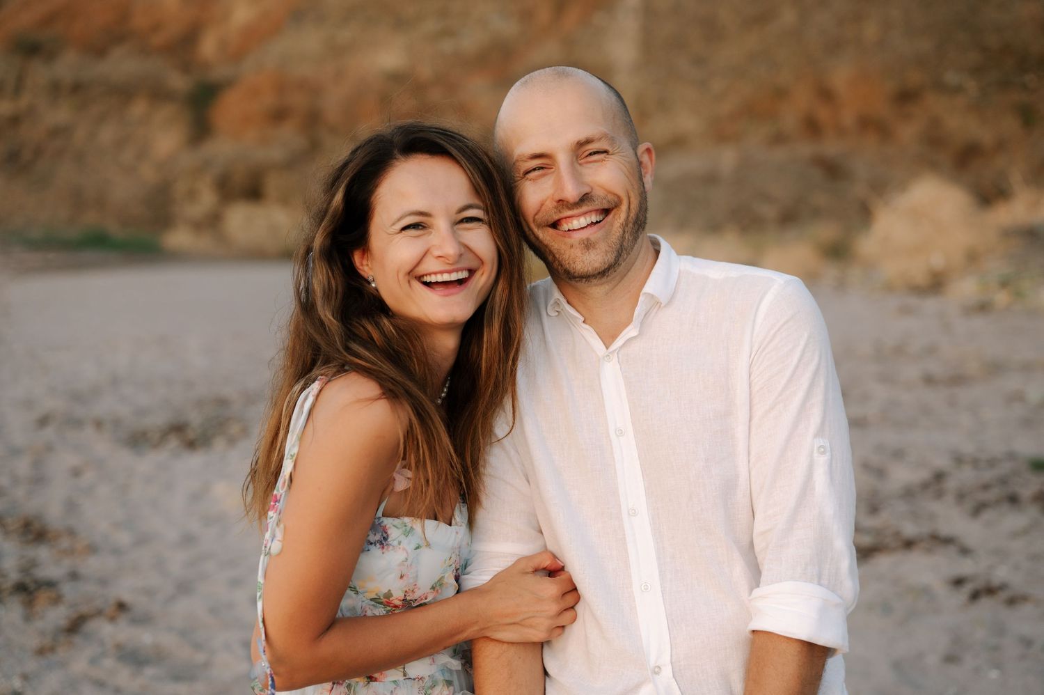 A couple shares joyful moments together during a sunset photoshoot on a beach.