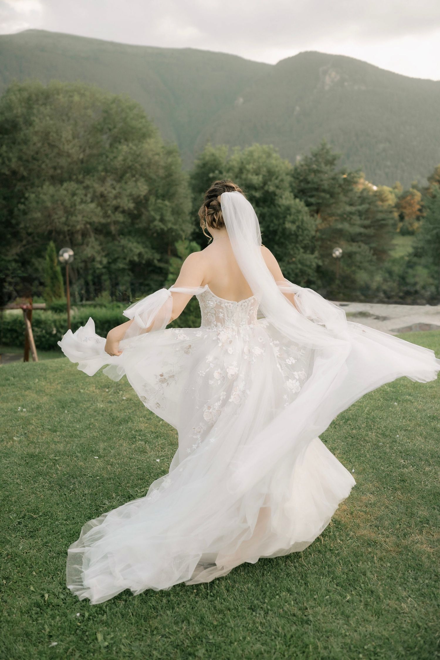 A bride spins in her elegant white gown creating a flowing movement against a mountain landscape.