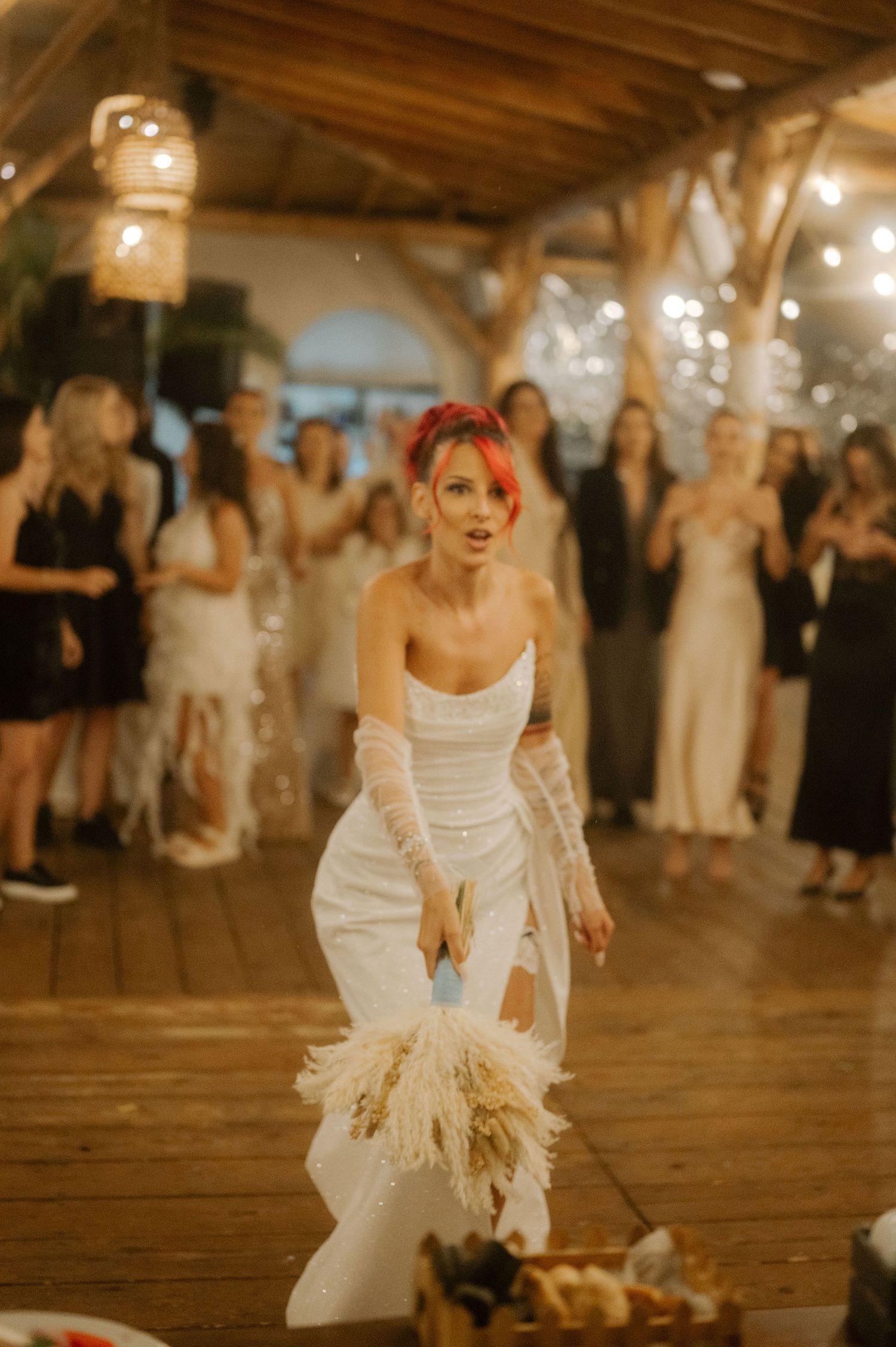 A wedding reception dance sequence showing someone in a white dress with feather details twirling on a wooden floor.