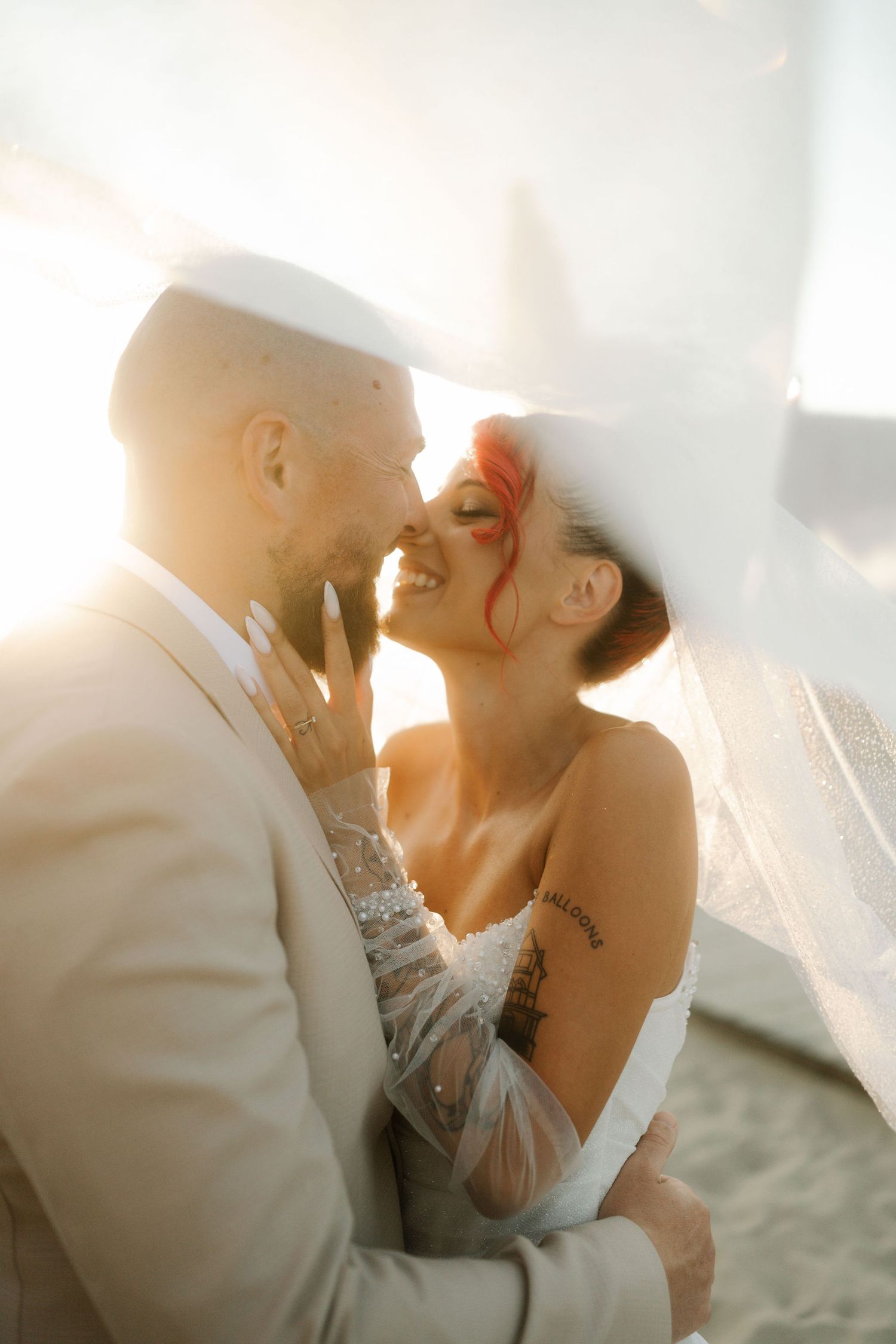 A romantic couple shares an intimate moment at sunset with a dreamy, backlit glow creating a soft silhouette effect.