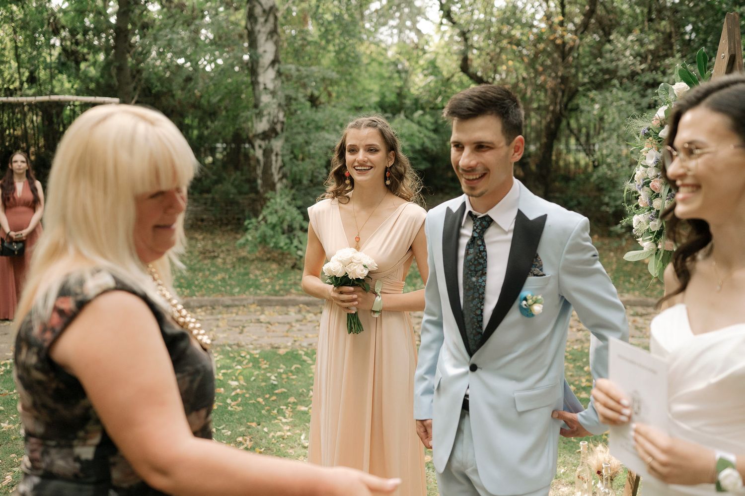 A joyful outdoor wedding celebration with guests mingling and laughing in a natural garden setting.