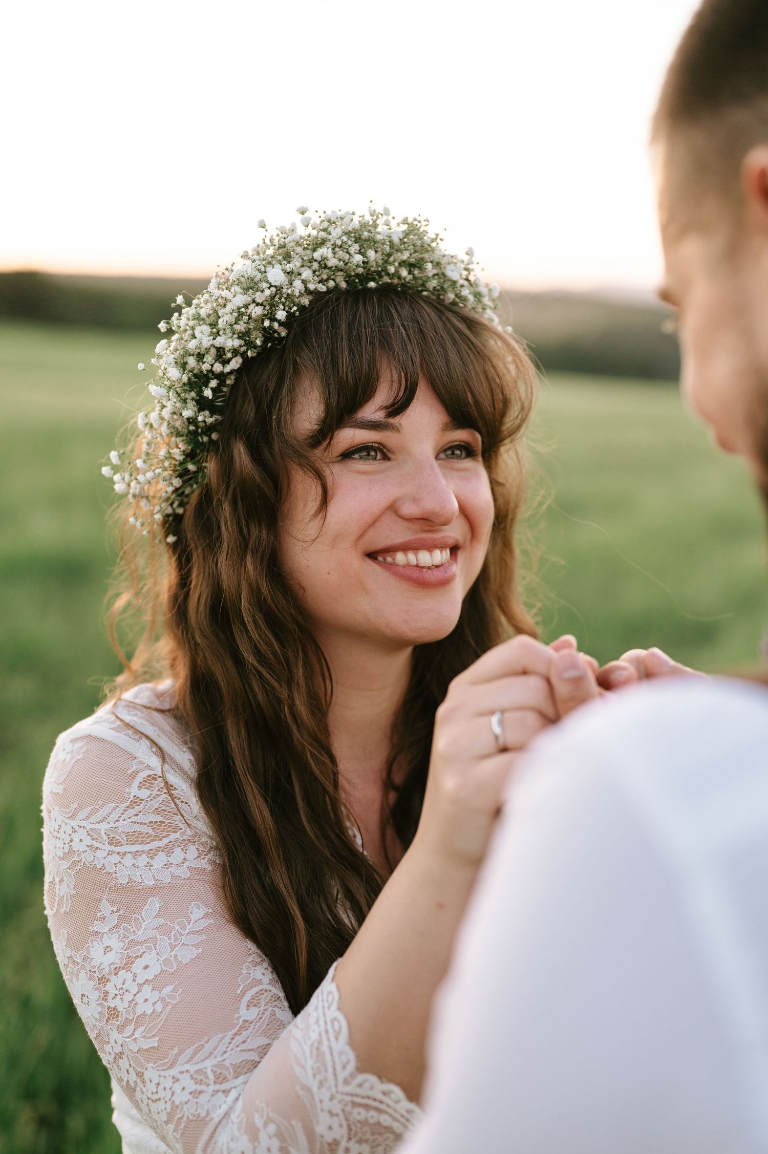 A bride in a delicate flower crown smiles during an outdoor portrait session.