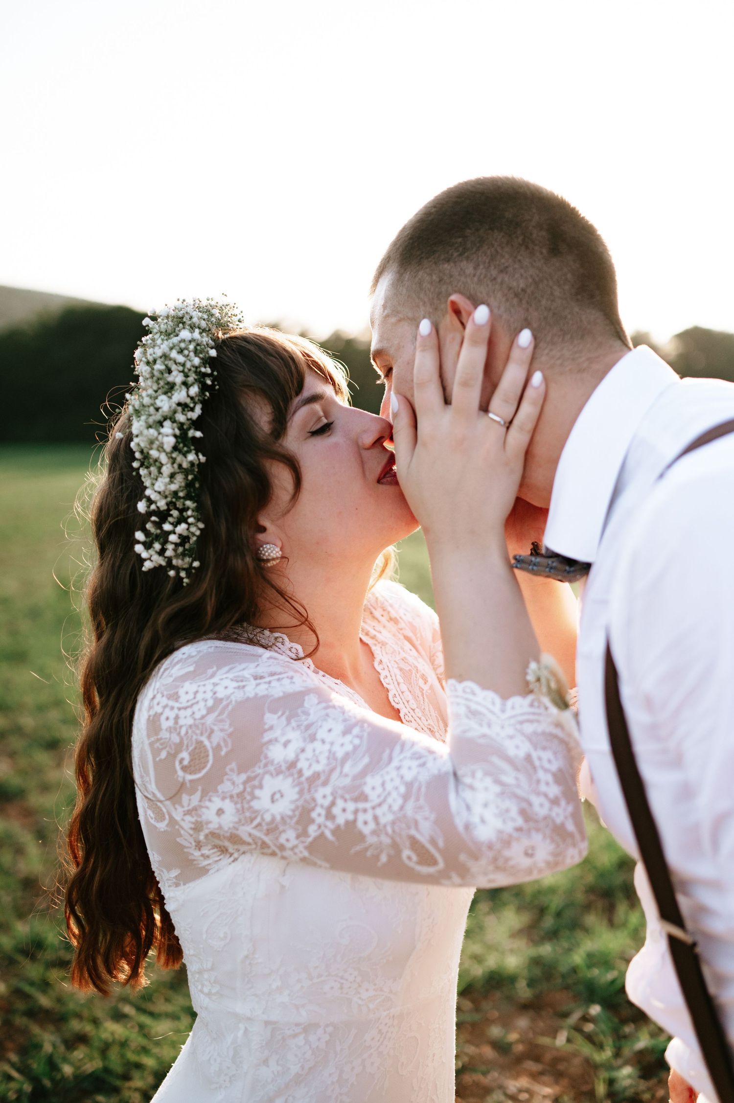 Wedding couple embraces tenderly during sunset photoshoot in a natural outdoor setting.
